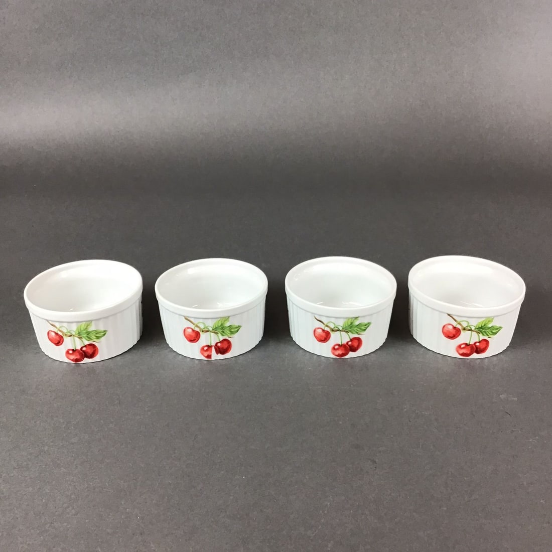 Set of 4 Seymour Main Inc Oven to Table Ramekins, Cherry Berry: This set of 4 ceramic ramekins is produced by Seymour Main Inc. and features an oven-to-table design. The circular dishes are crafted with fluted exterior walls and smooth interiors. Each ramekin is d