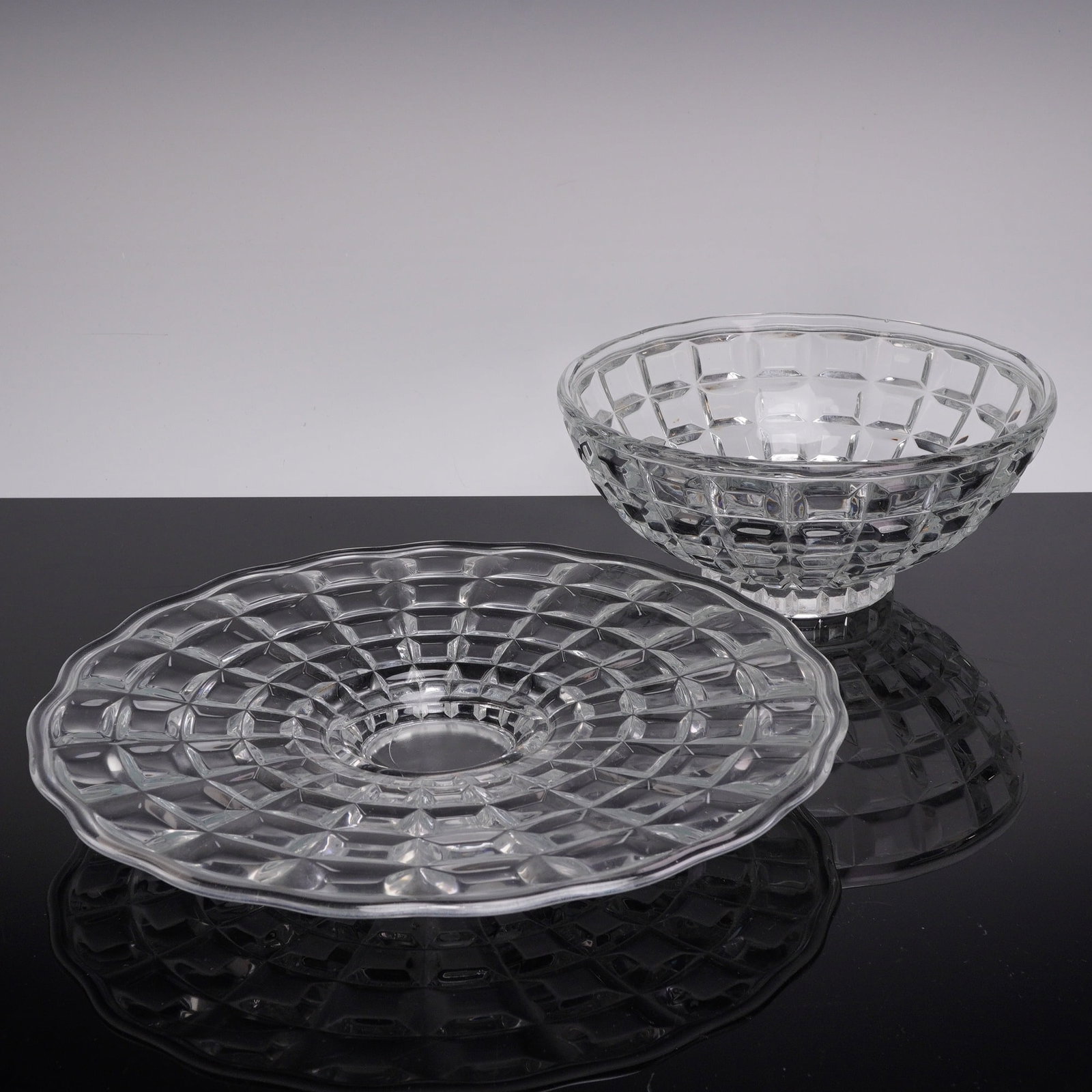 A Set of Two Crystal Glass Cut Block Pattern Serving Bowl & Plate: This set of two heavy, quality glass pieces comprises one bowl and one plate. The clear crystal glass is decorated with concentric rings of raised, convex rectangular blocks. The round serving plate f