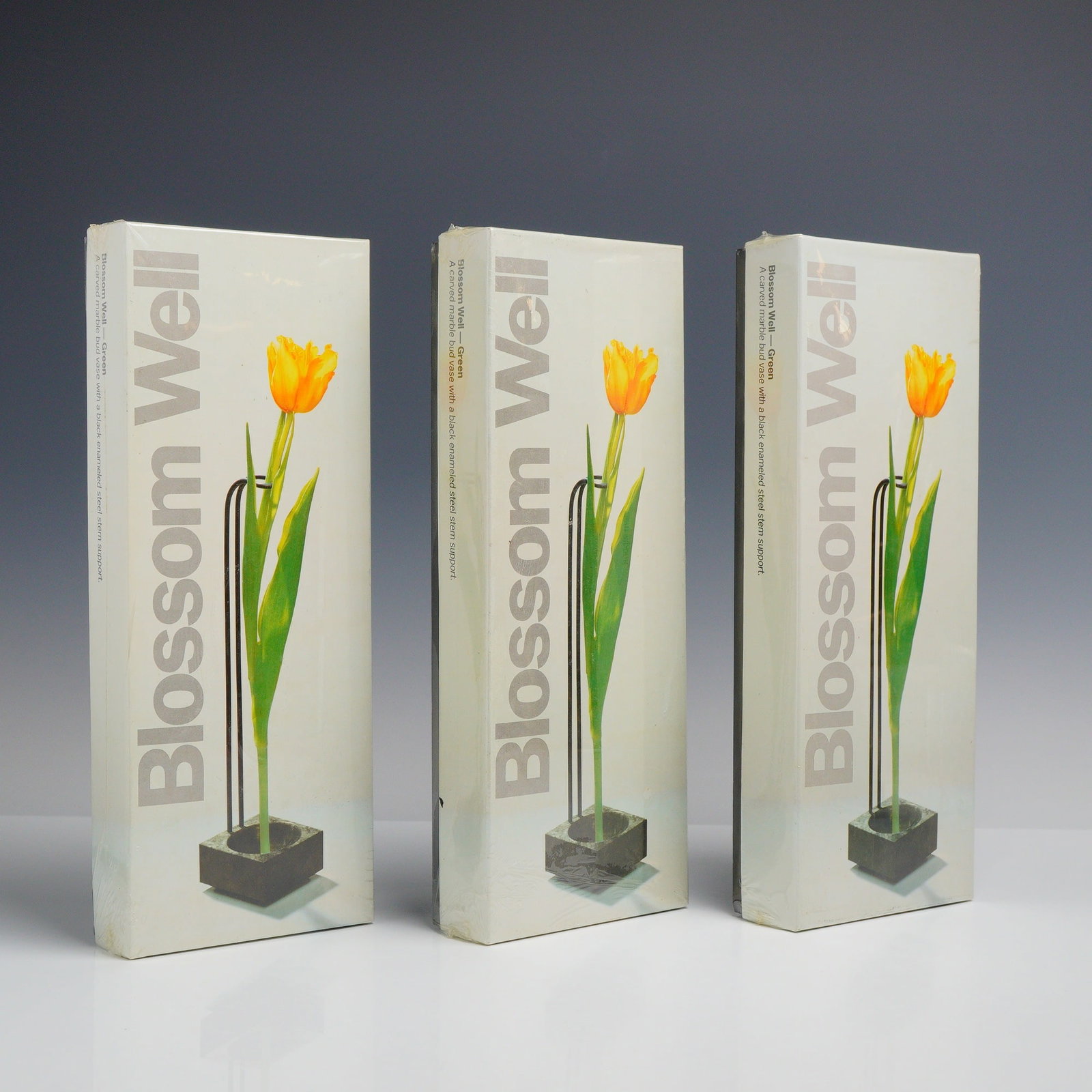 Three Boxed Peter Hewitt Blossom Well Marble Bud Vases: Three Blossom Well bud vases designed by Peter Hewitt, dated 1989. Each fine art plant vase is constructed with a carved green marble base and a black enameled steel stem support. The packaging identi