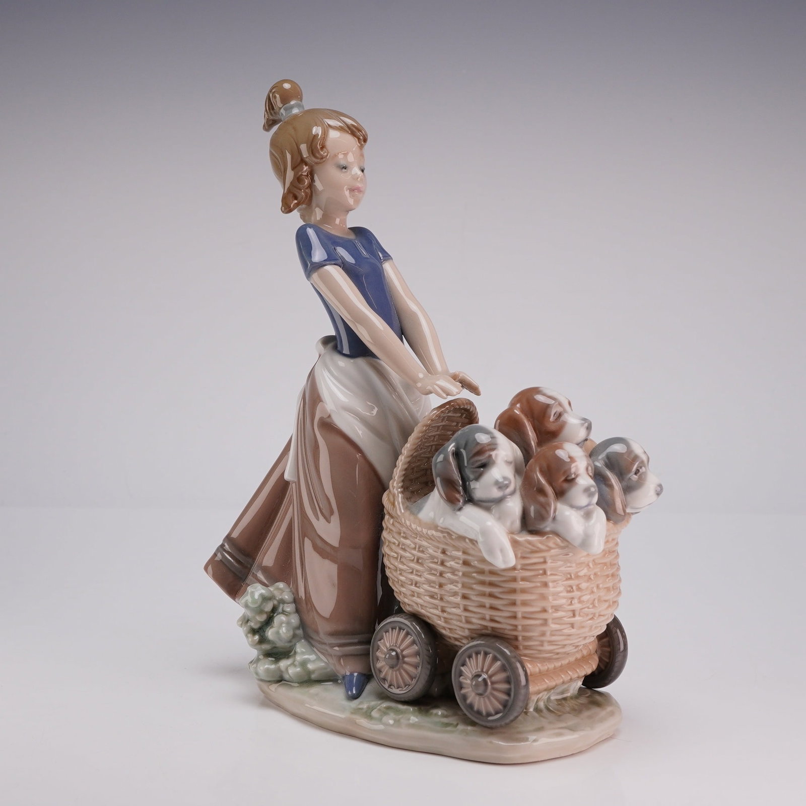 Lladro Porcelain Figurine Litter of Fun 01005364: A Lladro glazed porcelain figurine titled Litter of Fun, model number 5364. This piece was sculpted by Jose Roig and depicts a young girl with her hair in a ponytail, wearing a blue short-sleeved top 