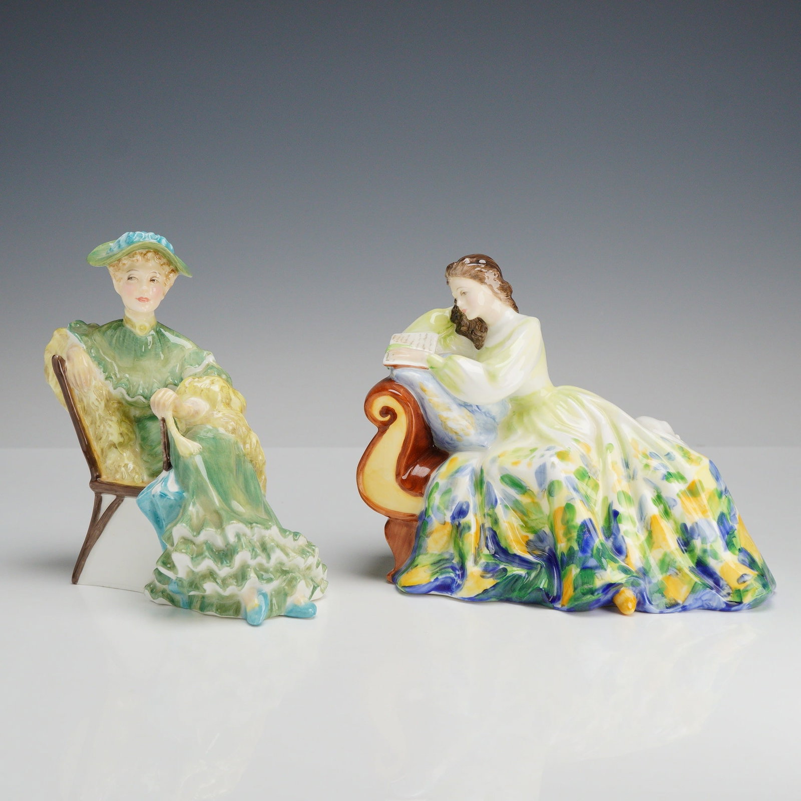 Two Royal Doulton Figurines, Ascot HN2356 and Solitude HN2810: This lot consists of two Royal Doulton figurines made of glazed bone china. The first figurine, titled Ascot (HN 2356), depicts a seated female figure in a ruffled green gown and a wide-brimmed green 