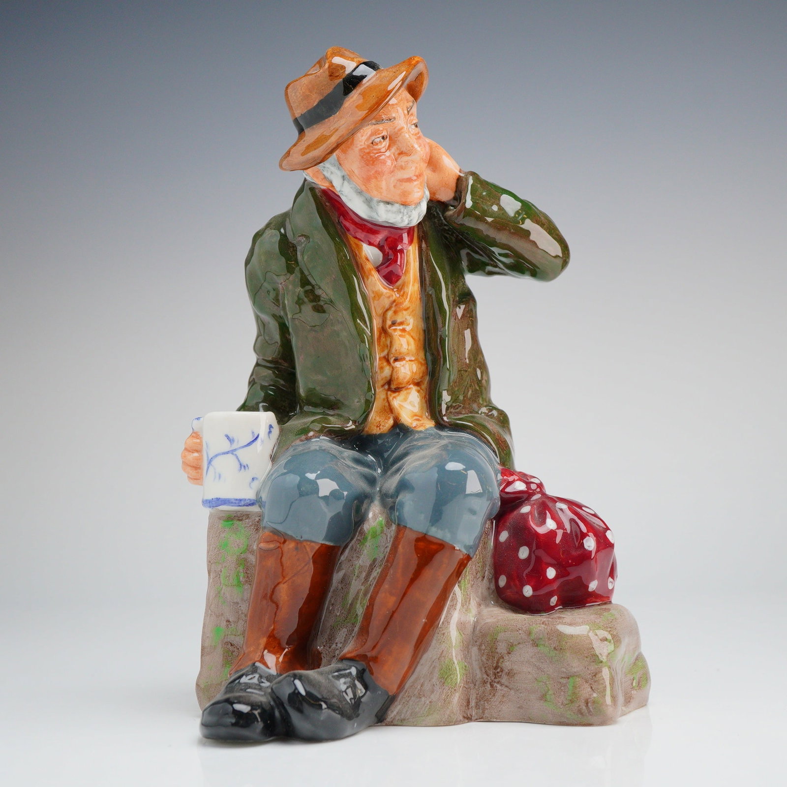 Royal Doulton Porcelain Figurine, Owd Willum HN2042: A Royal Doulton porcelain figurine titled Owd Willum, model number HN2042. This ceramic figure depicts an elderly man with a white beard seated on a stone outcrop. The subject is portrayed in traditio