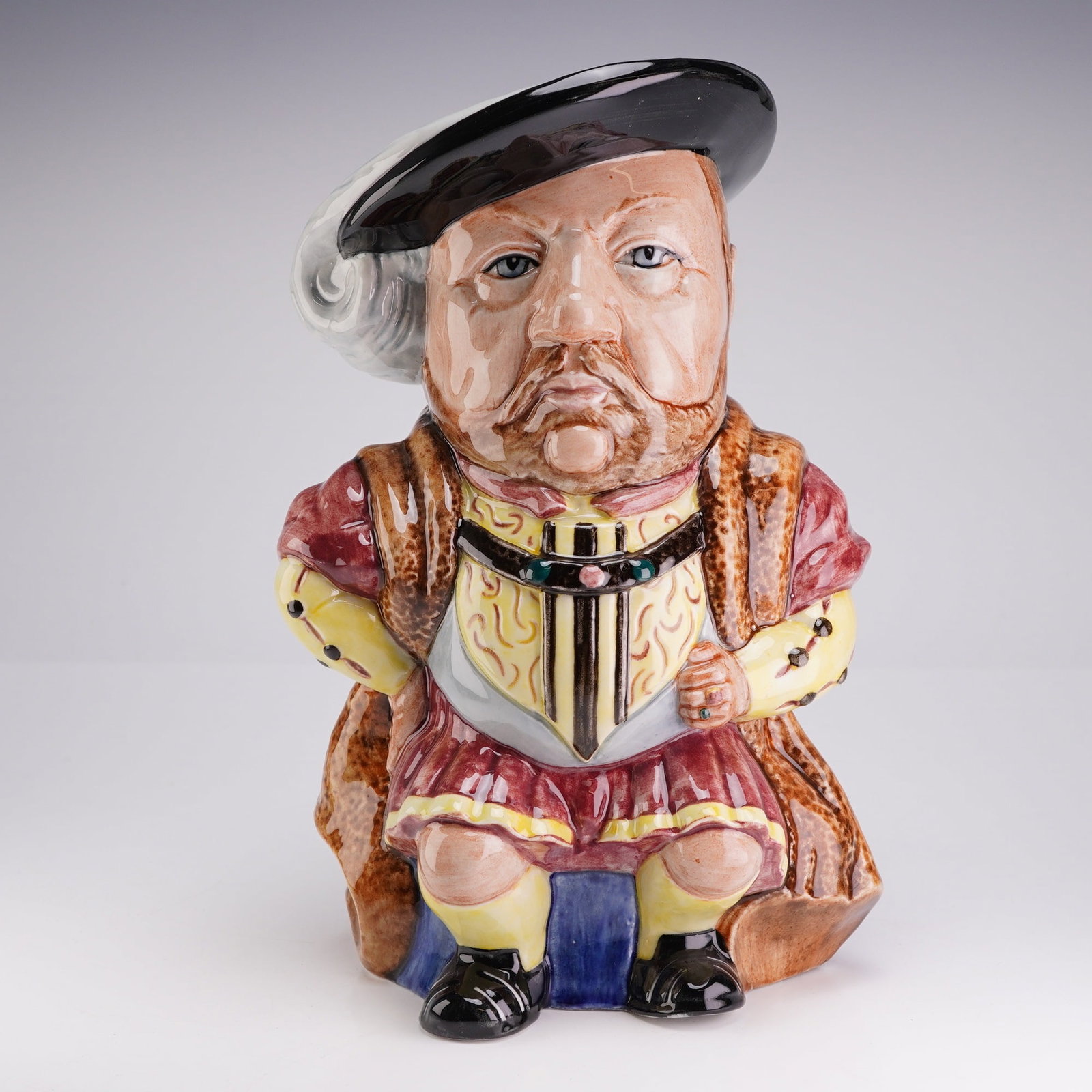 Staffordshire Fine Ceramics King Henry VIII Full-Figure Toby Jug: This glazed earthenware full-figure Toby jug is a product of Staffordshire Fine Ceramics, manufactured in England, model number 724. The jug depicts a seated figure of King Henry VIII positioned on a 