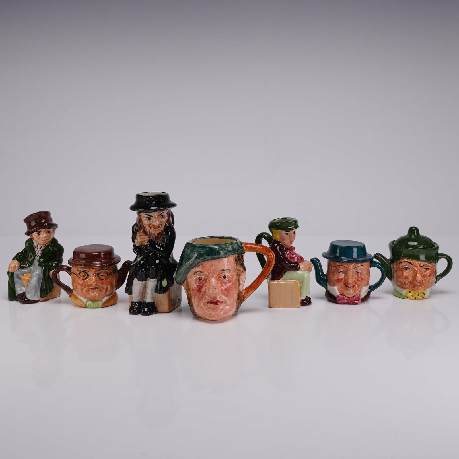 7pc Artone and Lancaster Sandland Miniature Character & Toby Jugs and Teapots: This collection consists of seven miniature ceramic items of English origin, featuring pieces from Artone and Lancaster Sandland. The group includes four character jugs and three Toby figures, all cra