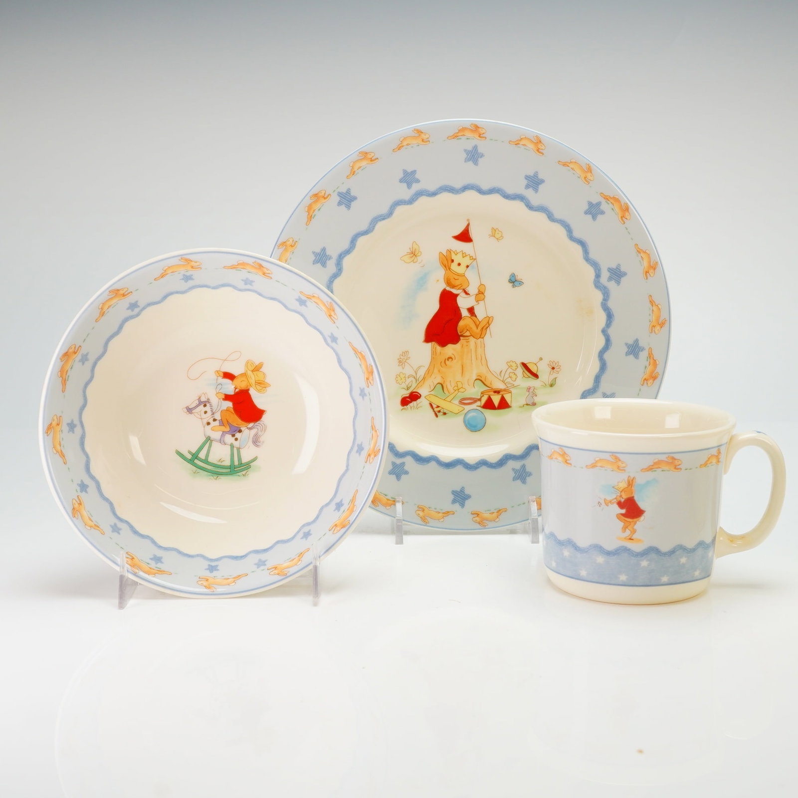 Royal Doulton Bunnykins Three-Piece Nurseryware Boxed Set: This fine china set is decorated with characteristic anthropomorphic rabbit illustrations in various scenes. The collection consists of a plate, a cereal bowl, and a handled mug, housed in the origina