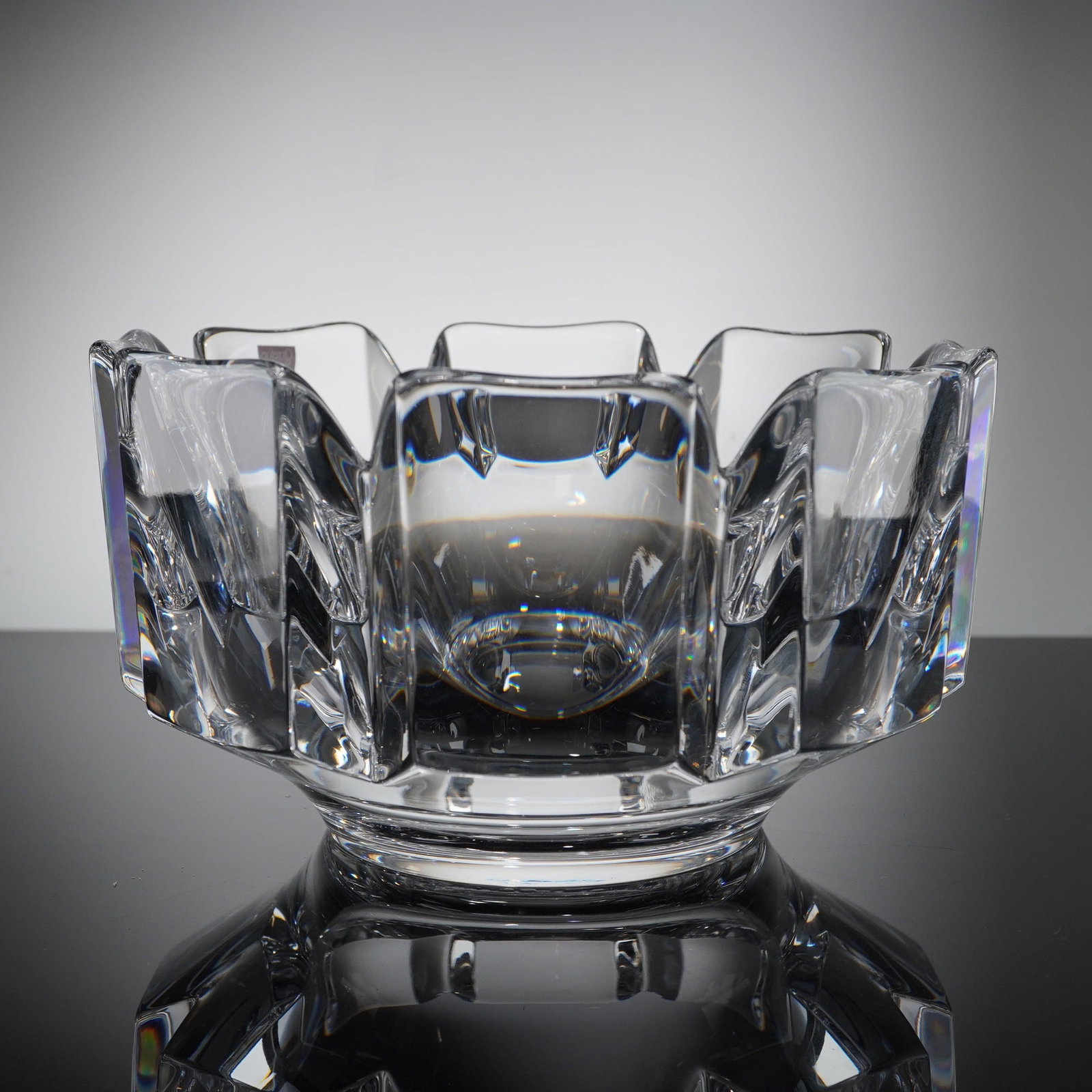 Orrefors Crystal Corona Bowl: A single piece of clear crystal atributed to the Swedish manufacturer Orrefors. The object appears to be the thick, refractive base or underside of the bowl. The material is characteristic of high-qua