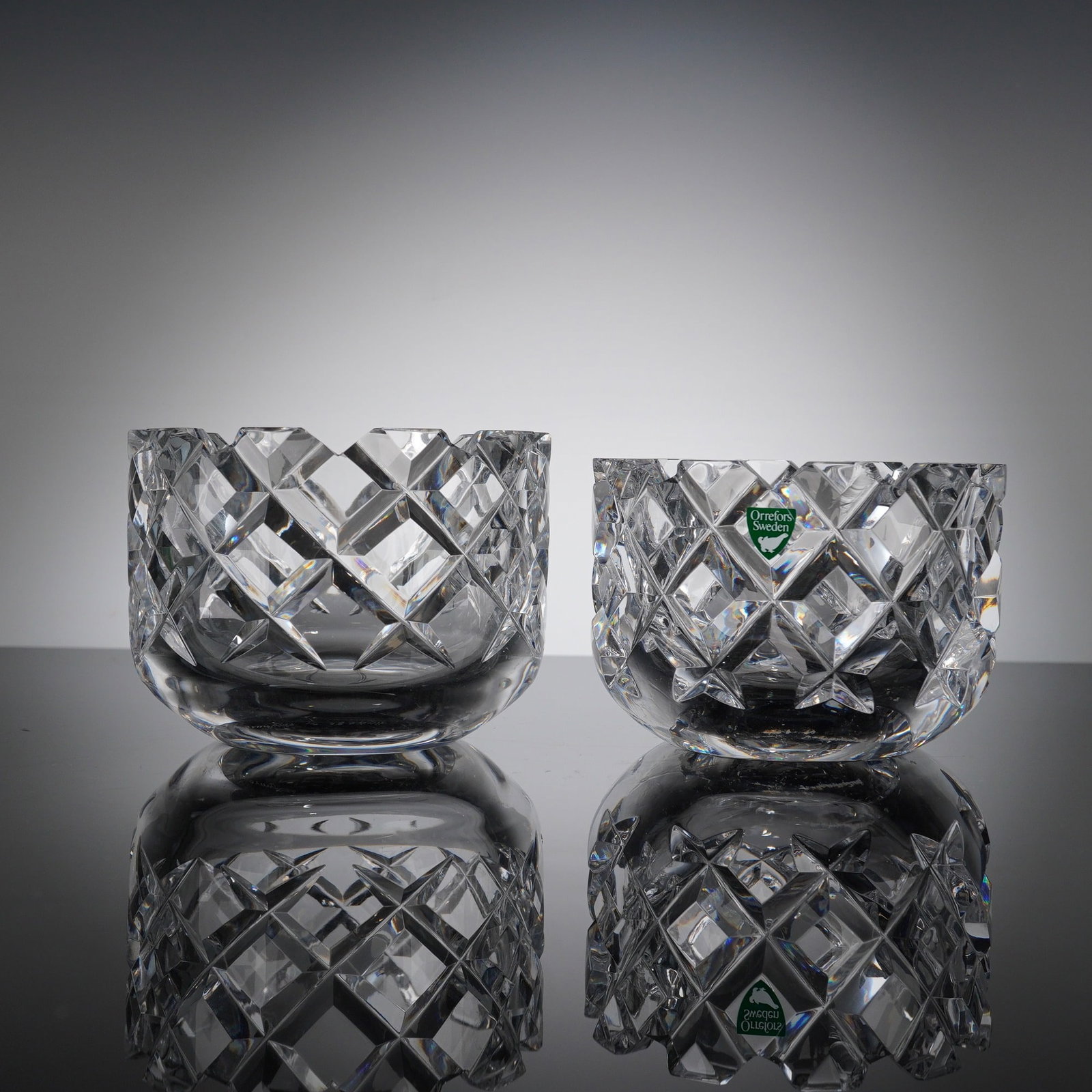 Pair of Orrefors Sweden Crystal Candleholders, Sofiero: A set of two clear crystal candleholders from Orrefors' iconic Sofiero collection, designed by Gunnar Cyren. Renowned as a Scandinavian glass classic. The design features the signature deep-cut patter