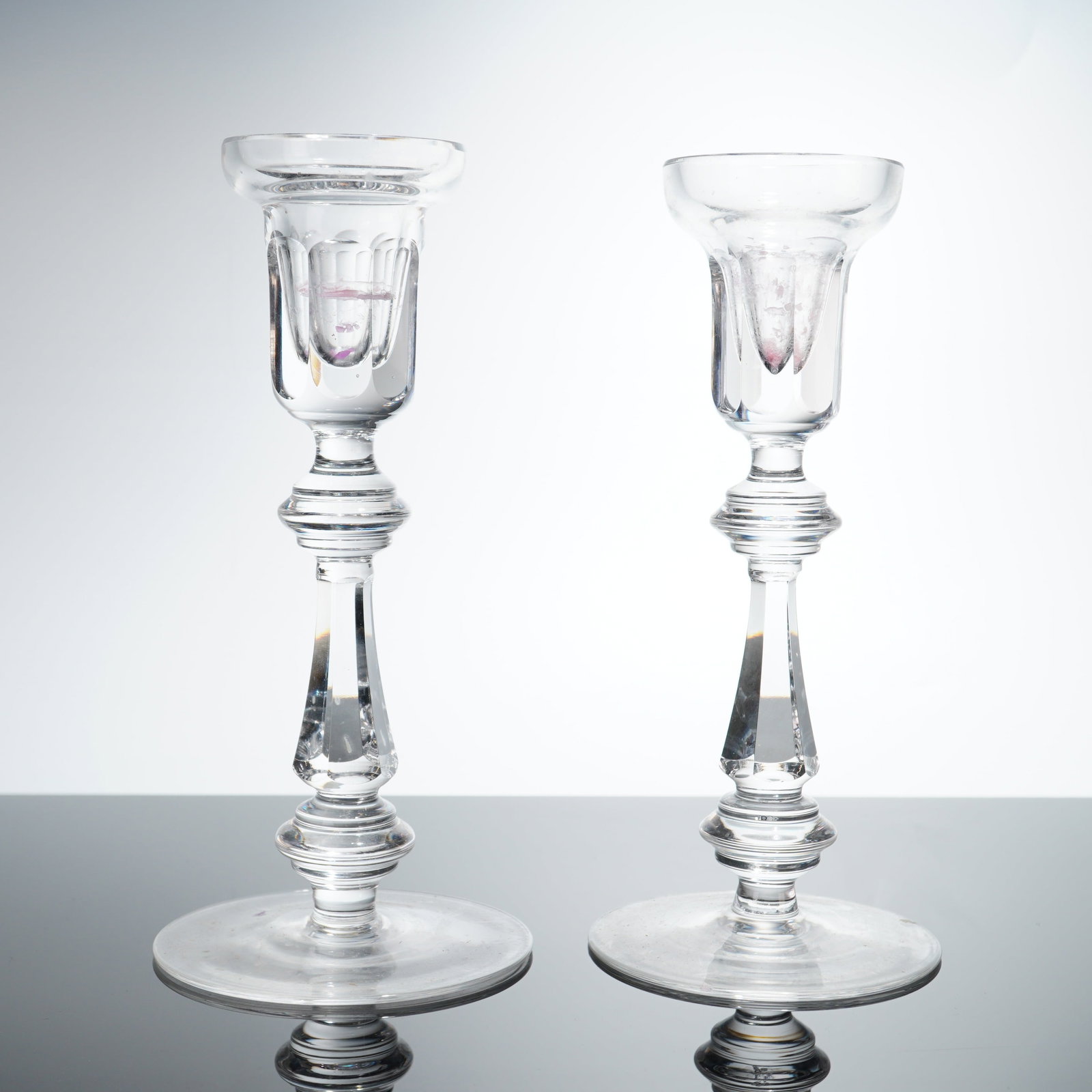 Pair of Waterford Cut Crystal Baluster Stem Candlesticks: A pair of Waterford cut crystal candlesticks. The design features a flared rim candle cup decorated with vertical panel cuts around the lower portion. The multi-part stem consists of a ringed knop sit