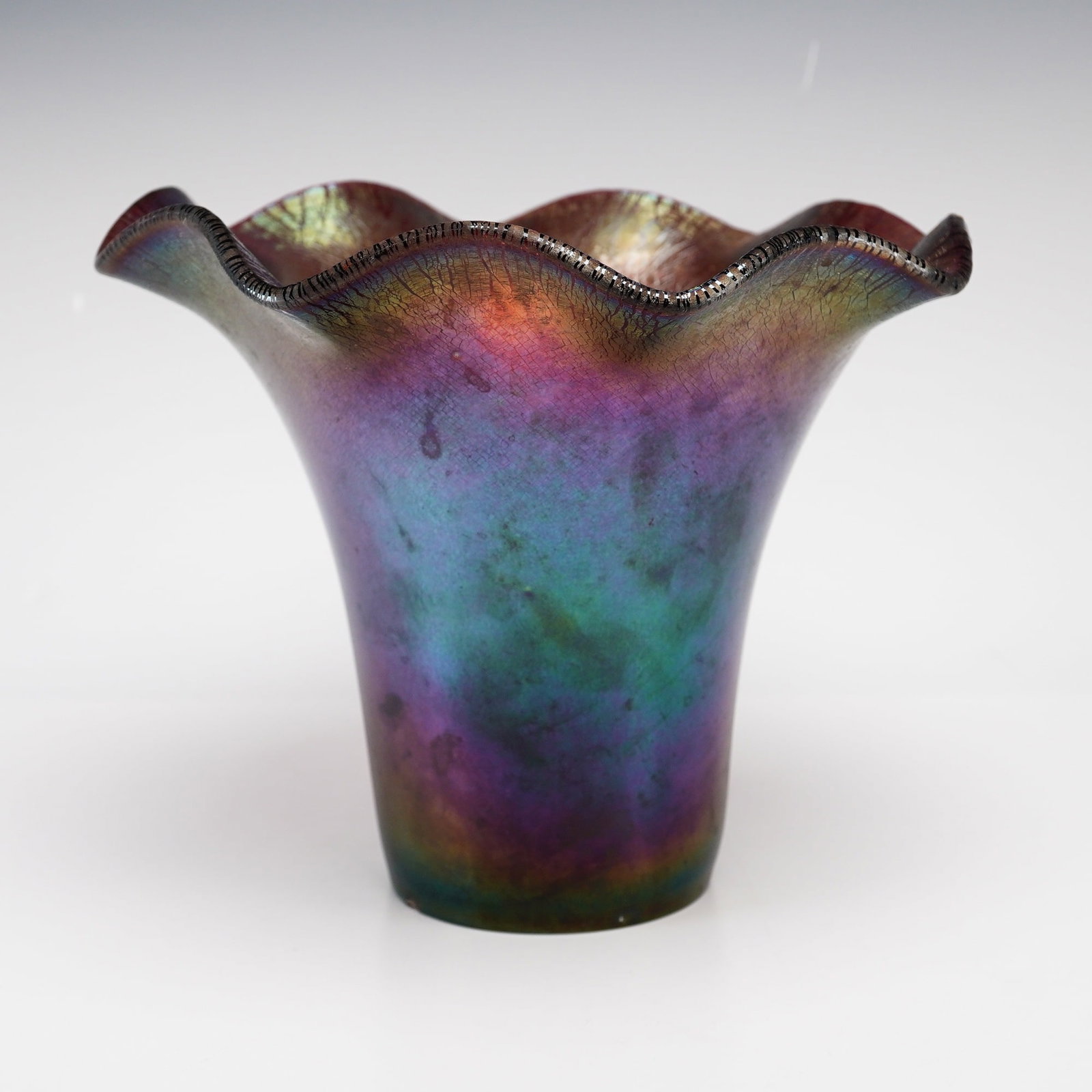 Imperial Glass Amethyst Carnival Glass Vase Post 1972: An Imperial Glass carnival glass vase manufactured post 1972. The vessel is composed of amethyst glass and features a widely flared, ruffled rim transitioning into a tapering cylindrical body. The ext