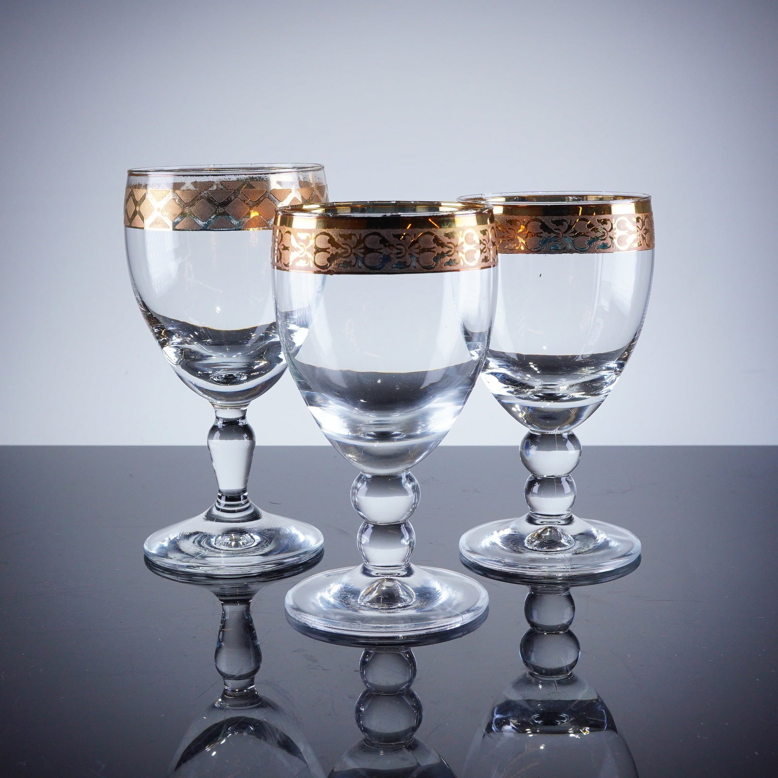 3pc Gold Rim Crystal Wine Glasses: A trio of stemmed drinking glasses, featuring heavy gold-gilt decoration applied to the rim and upper bowl section. The decoration consists of a solid gold band at the rim, which two glasses display a