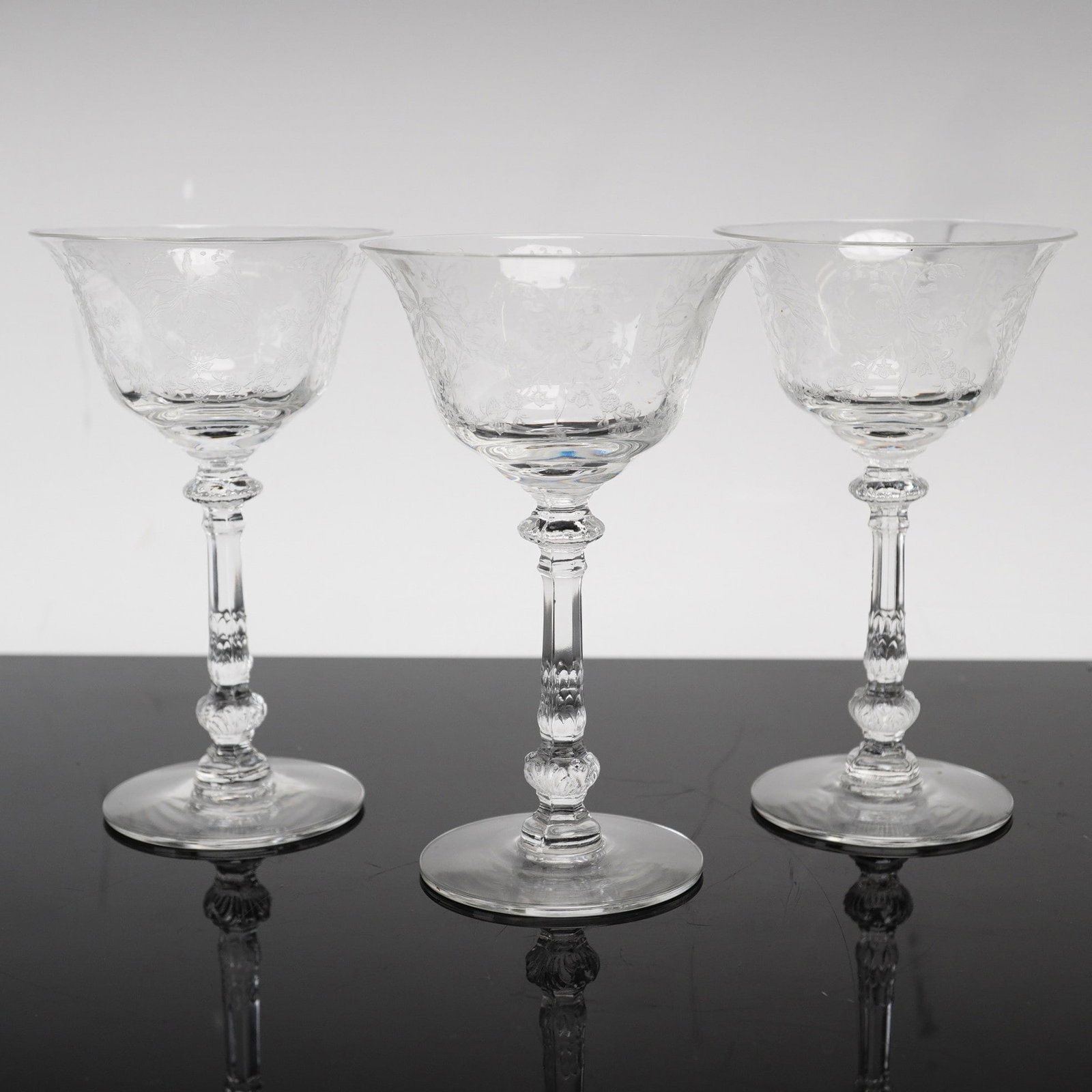 A Trio of Heisey Orchid Etched Crystal Champagne Coupes: This set of three lead crystal champagne coupes features the Orchid pattern by Heisey. Each glass is constructed with a wide, flared bowl decorated with a fine-line acid-etched floral and scroll motif