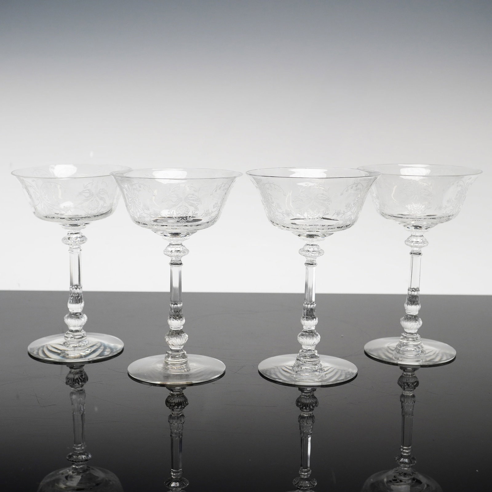 4pc Heisey Orchid Etched Crystal Champagne Coupes: This set of four crystal stemware glasses is produced by Heisey in the Orchid pattern. Each glass features a wide, shallow coupe bowl decorated with a fine-line acid-etched floral and foliate motif de