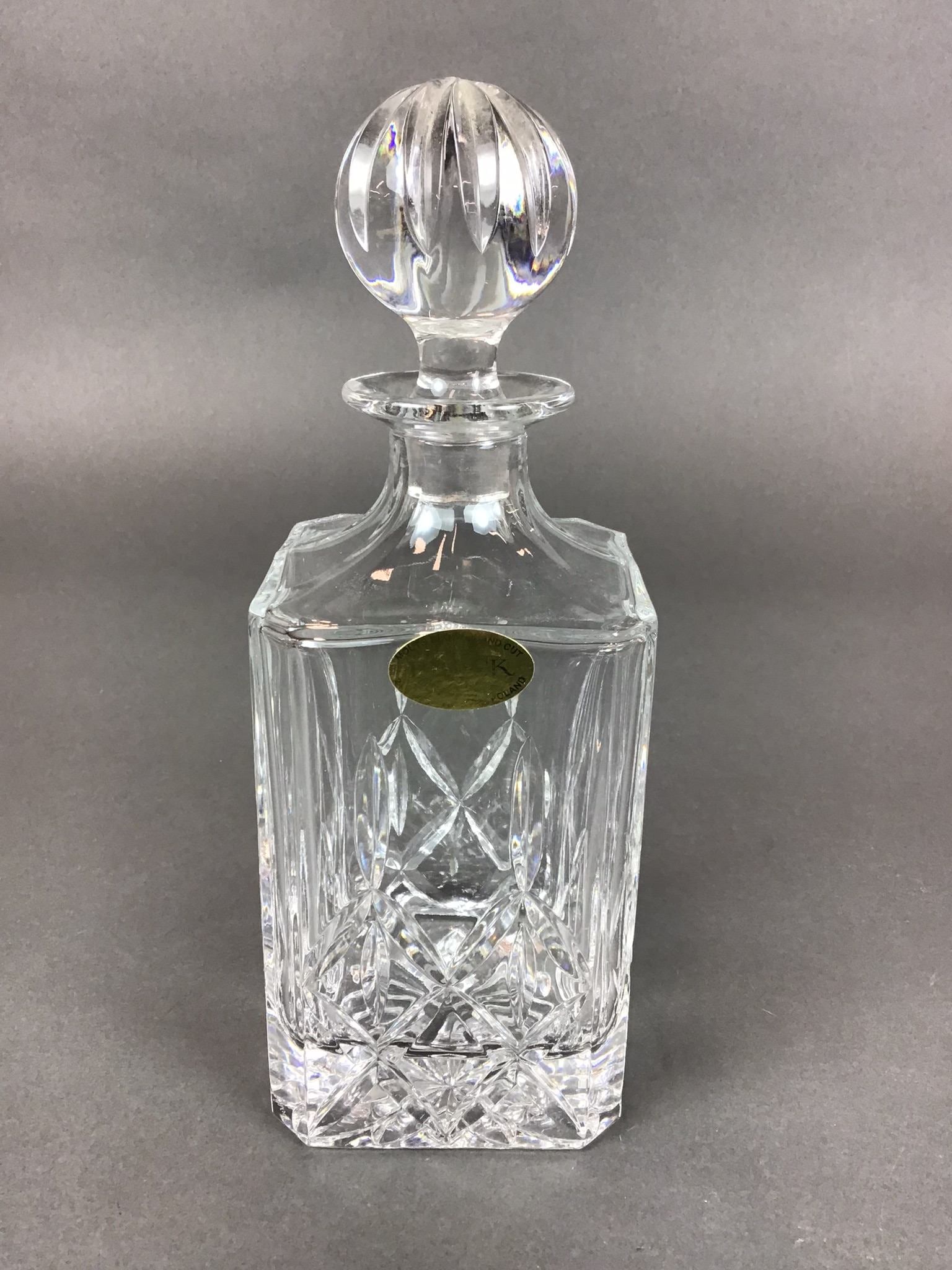 Brock Cut Crystal Decanter with Stopper: This Brock cut crystal liquor decanter is a heavy, square-form vessel crafted from 24 percent lead crystal. The piece features a complex, multi-tiered hand-cut design. The lower section of the body is