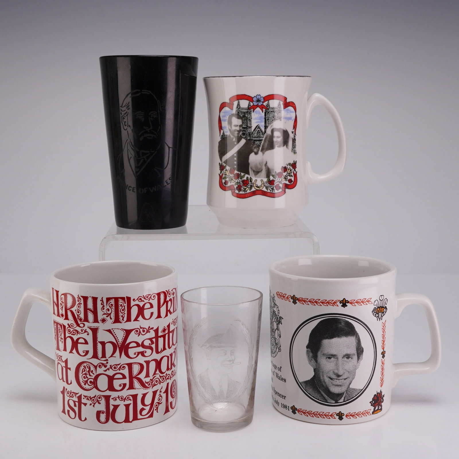 Collection of Five British Royal Commemorative Tableware: A collection of British Royal commemorative tableware including ceramic mugs and glassware. The collection features a white ironstone mug commemorating the 1981 marriage of the Prince of Wales and
