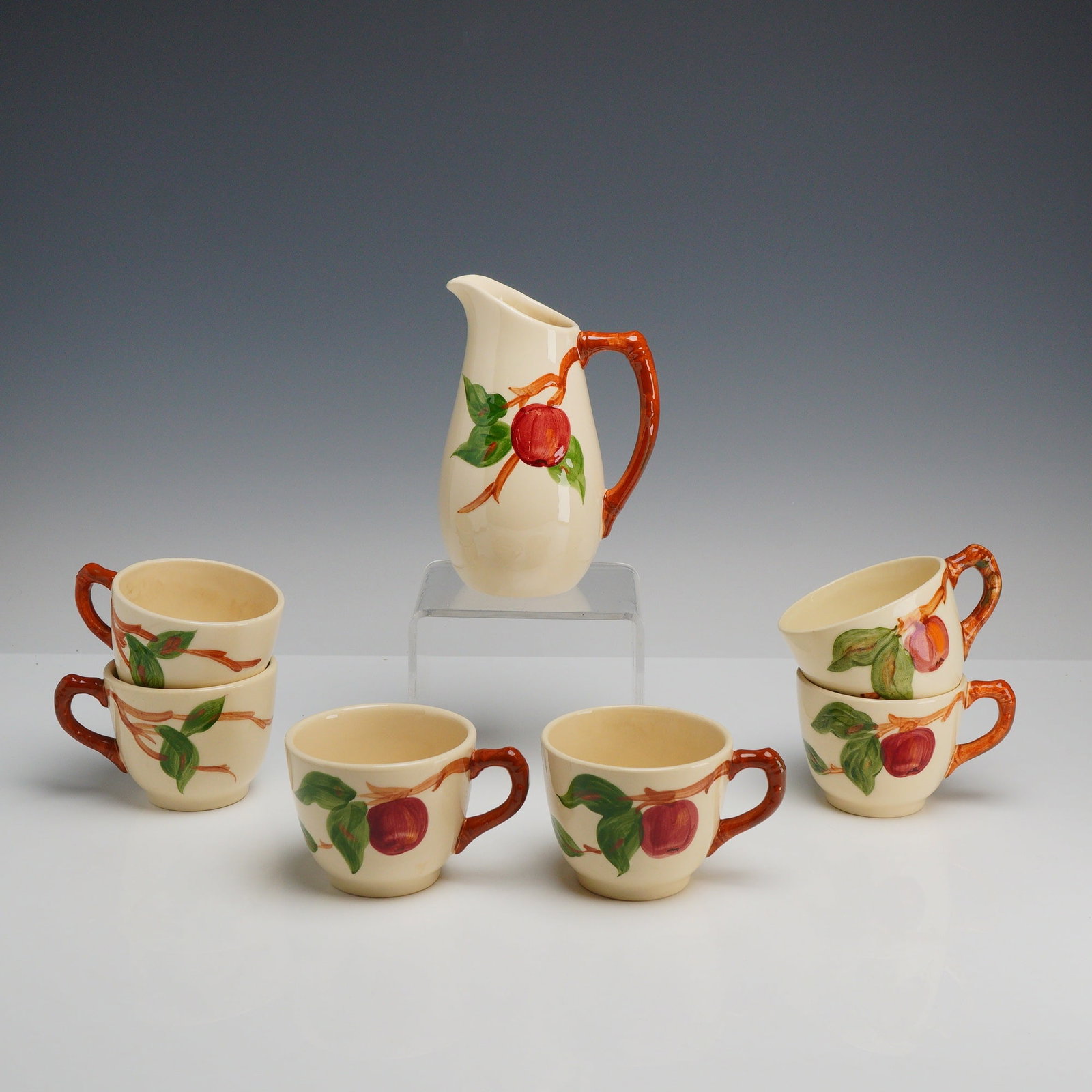 7pc Franciscan Earthenware Cups and Creamer Jug, Apple Tree: This 7pc Apple tree ceramic cups and creamer jug set is manufactured by Franciscan in the Apple pattern. The pieces are constructed from glazed earthenware and feature hand-painted underglaze decorati