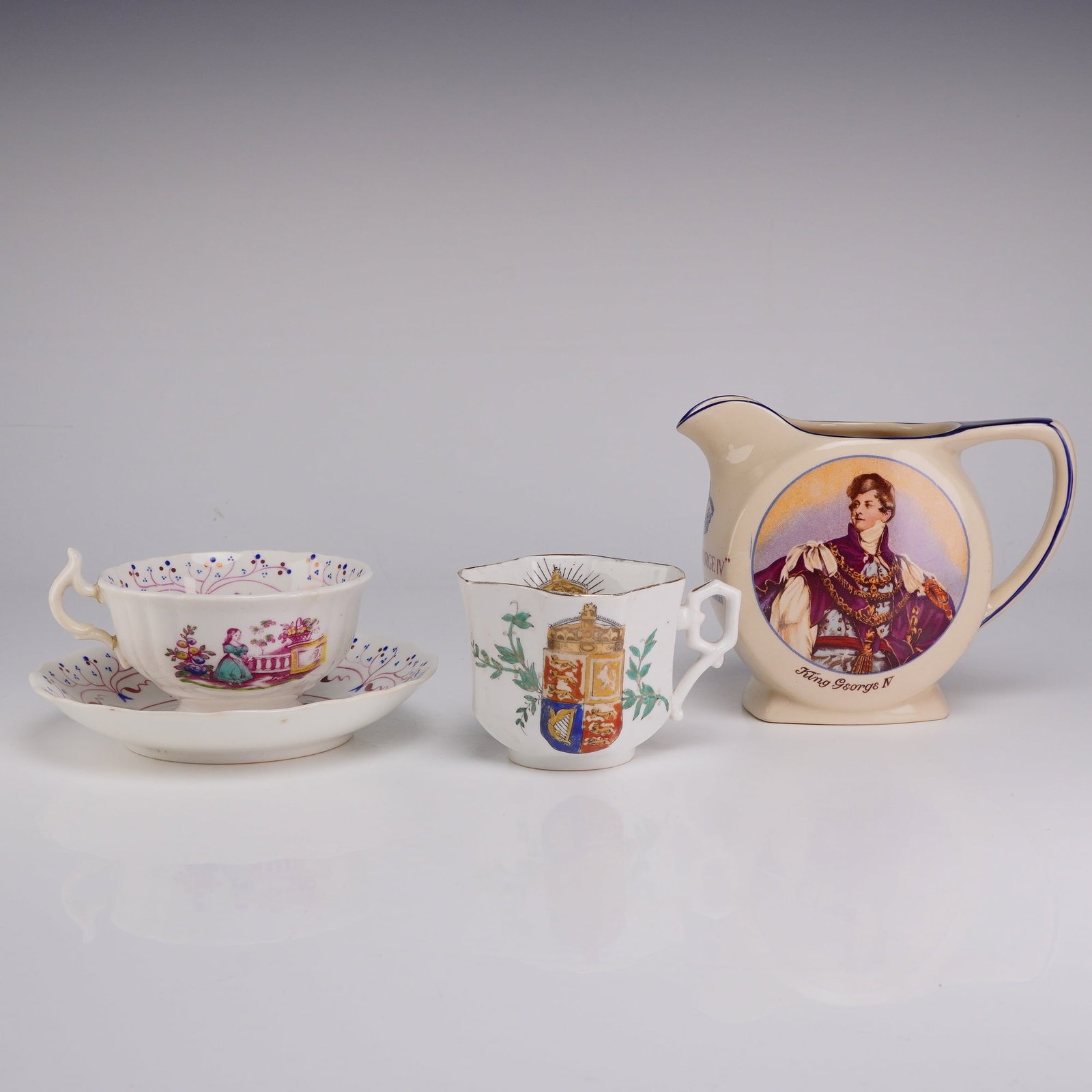 4pc British Royal Commemorative and Advertising Ceramics: An assortment of British royal commemorative and advertising ceramic pieces including a porcelain cup and saucer, a small faceted mug, and an earthenware pitcher. The porcelain cup and saucer are deco