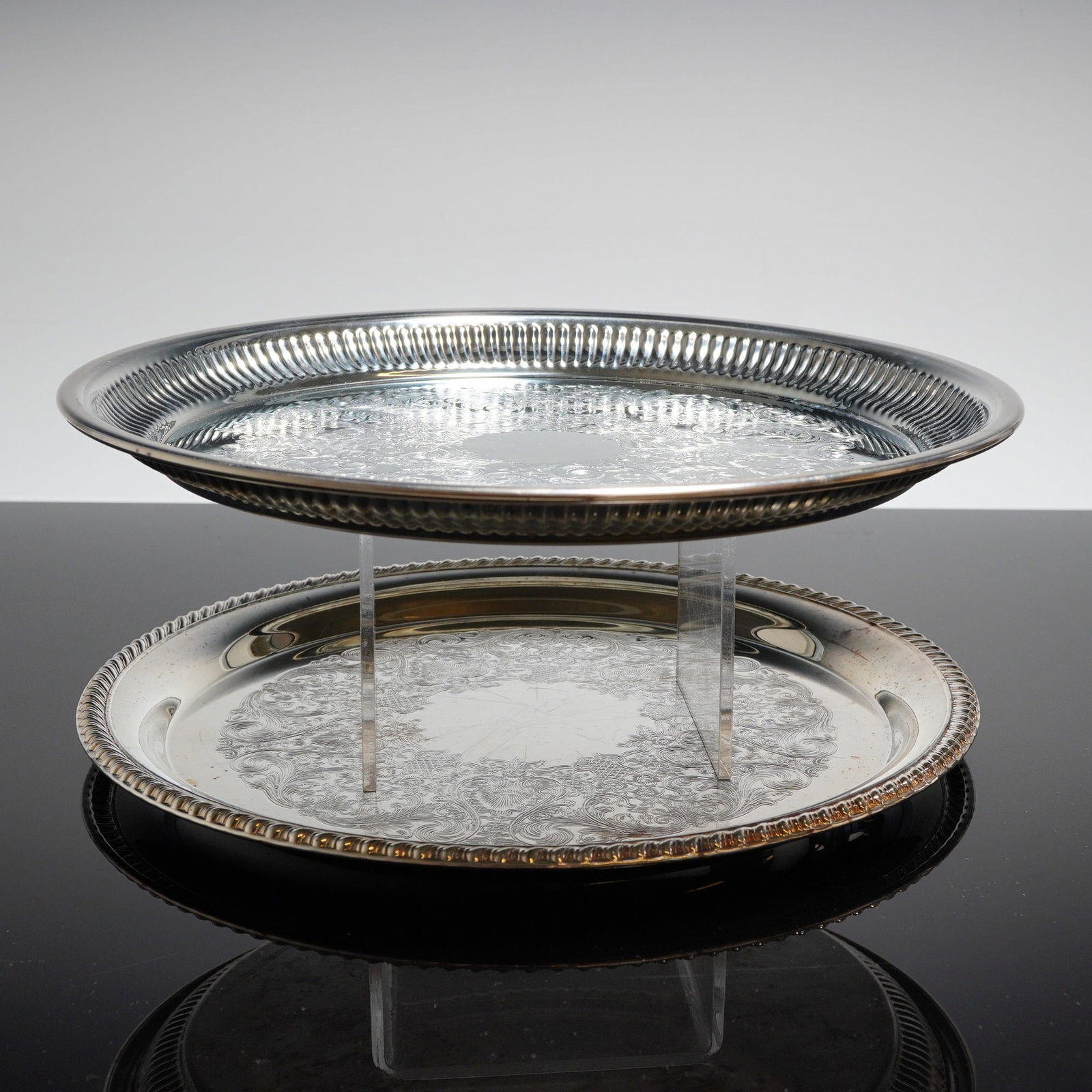 A Pair of Electroplated Serving Trays by Kent Silversmith & International: A pair of electroplated serving trays, one manufactured by Kent Silversmith, NC, USA, and the other by International Silver Co. The trays are circular and constructed of electroplated brass (EP Brass)