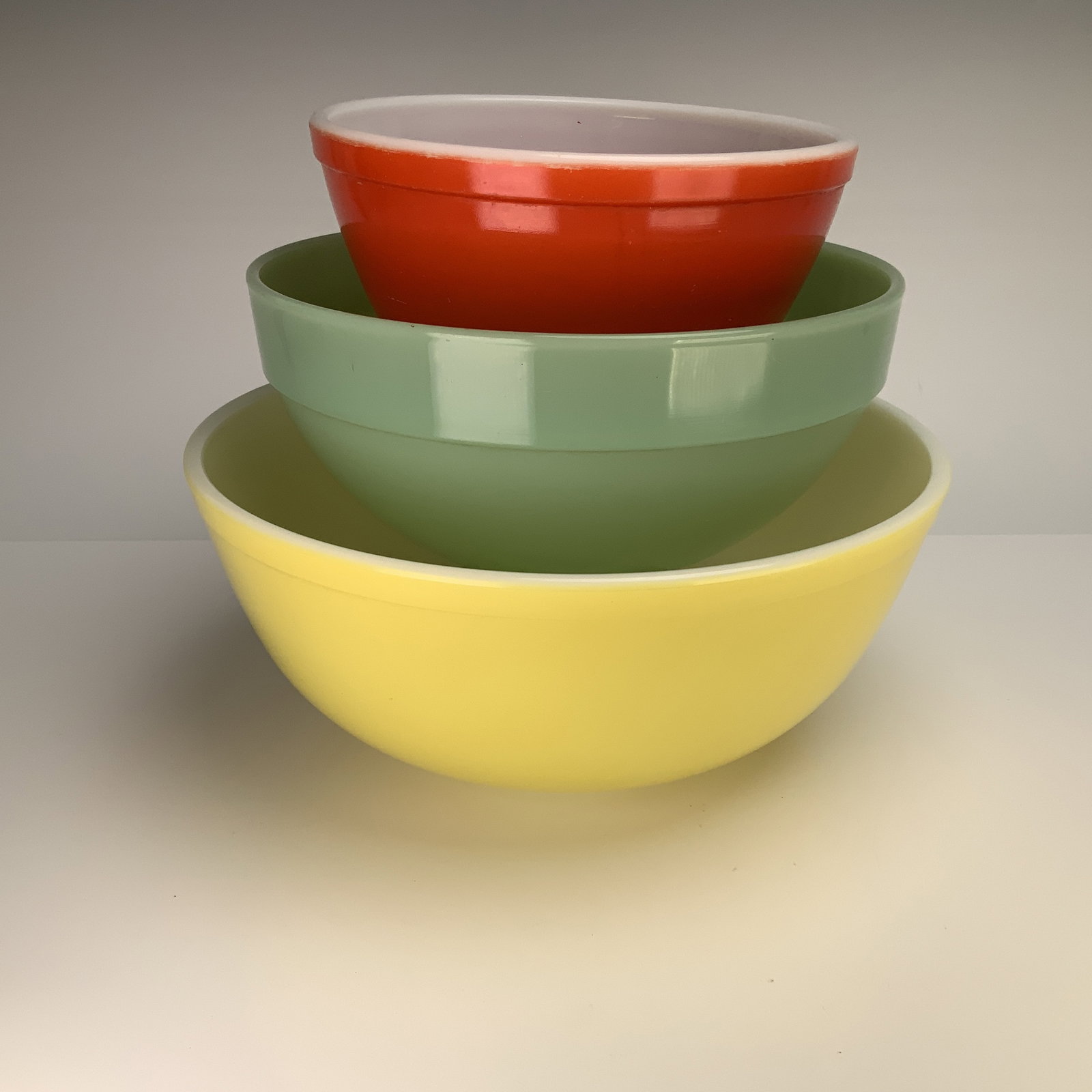 3pc Lot of Vintage Pyrex & Fire-King Glass Pastel Colors Mixing Bowls: This lot includes two Pyrex bowls and one Fire-King Ware green bowl in graduated sizes and pastel colors. The smallest bowl features a red-orange fired-on exterior color with a white interior and is e