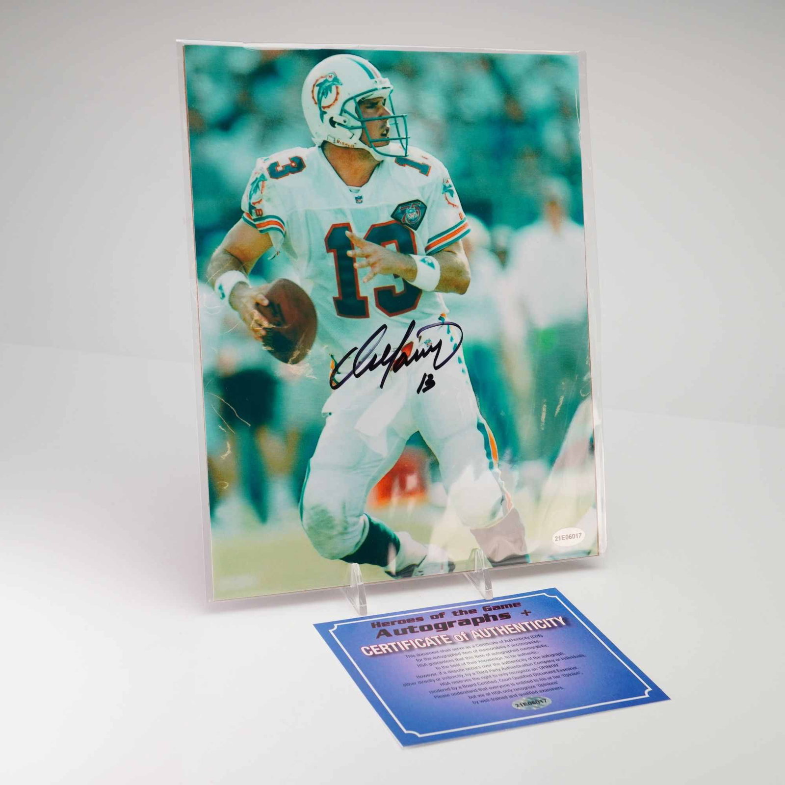 Dan Marino Signed Miami Dolphins Action Photograph with COA: An autographed color photograph of Pro Football Hall of Fame quarterback Dan Marino during his tenure with the Miami Dolphins. The photograph depicts Marino in a dynamic action pose, wearing the team 
