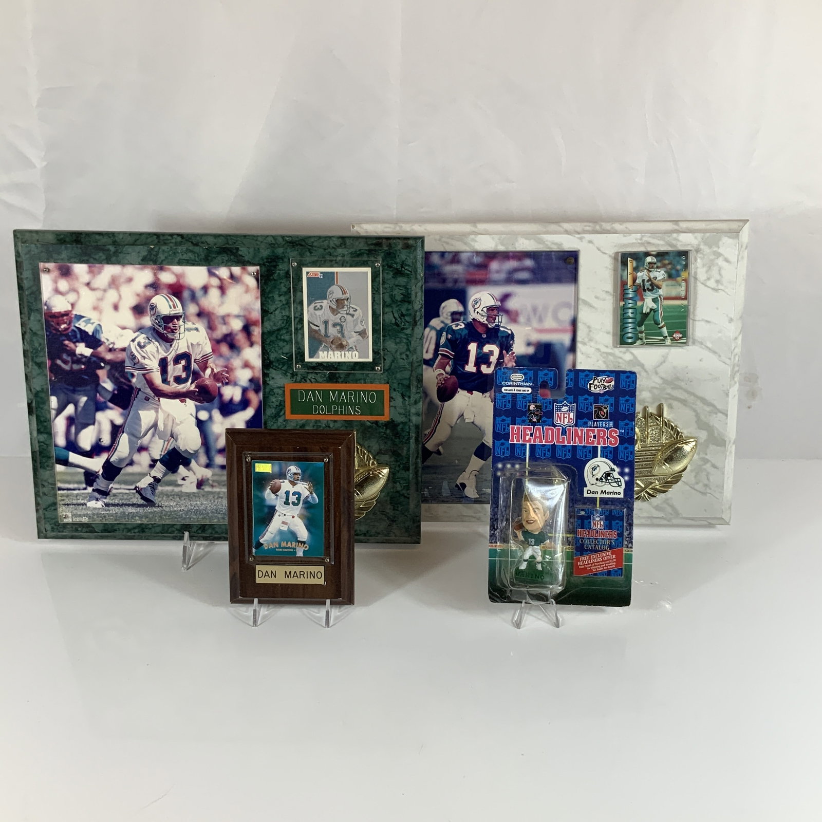 Collection of Four Dan Marino Miami Dolphins Sports Memorabilia Including Plaques and Figurine: This collection of Dan Marino Miami Dolphins sports memorabilia includes four separate commemorative items. The first is a multi-media display plaque with a green faux-marble finish. It features a