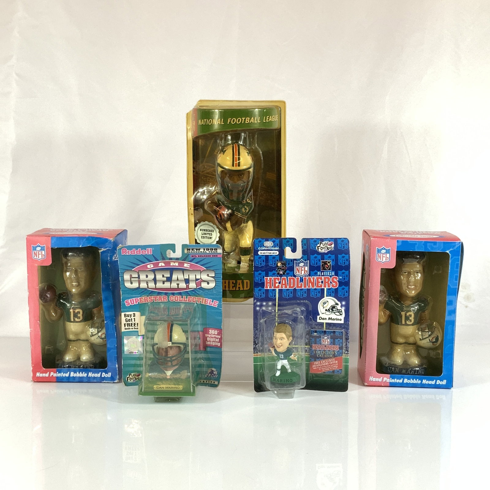 Collection of Five NFL Bobbleheads and Figurines Featuring Dan Marino and Brett Favre: The collection features several items depicting Miami Dolphins Hall of Fame quarterback Dan Marino, including two hand-painted Bobble Dobbles figures created for the NFL Quarterback Club. These figure