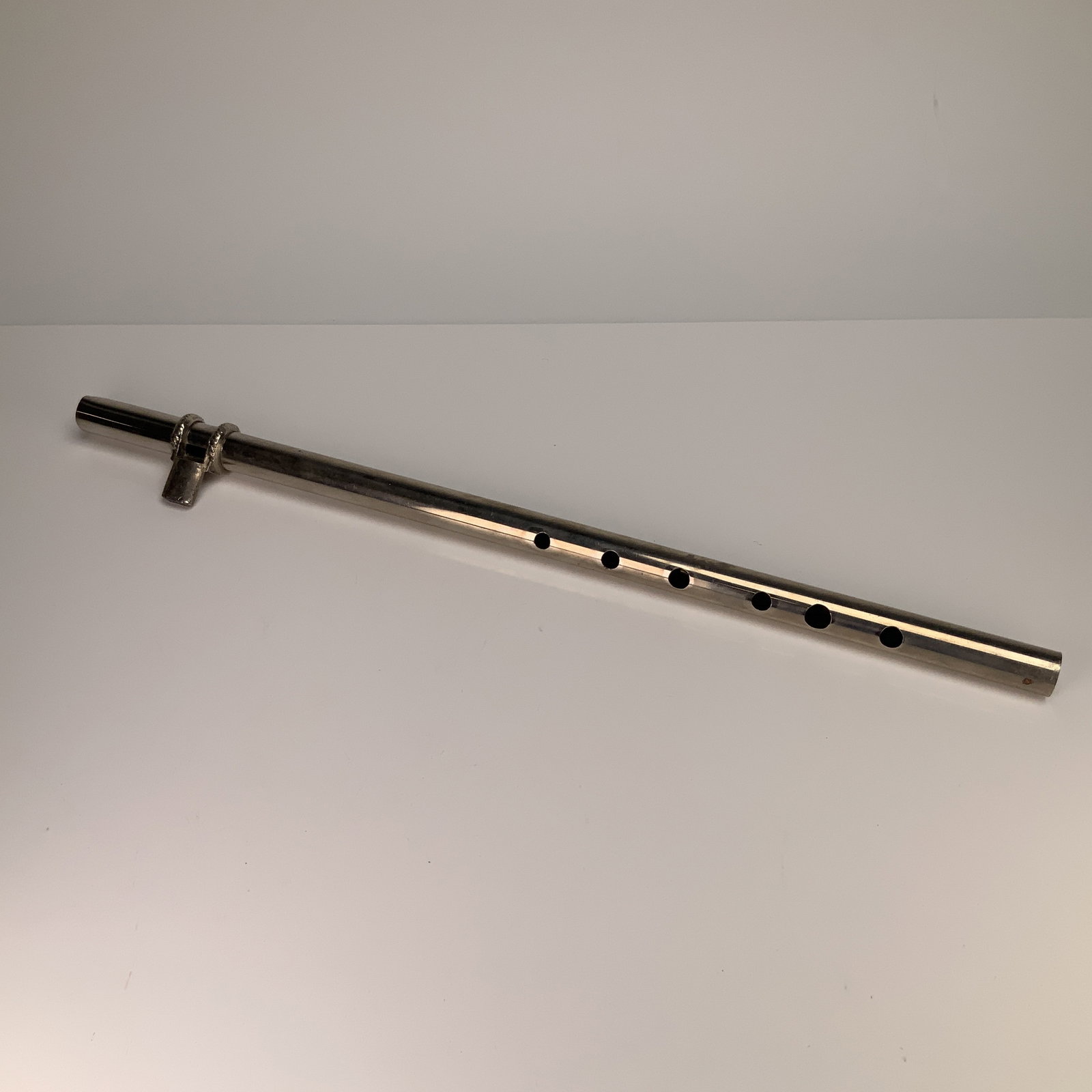 E355 Metal Six-Hole Whistle Recorder: The instrument features a cylindrical body with six tone holes. The mouthpiece assembly is joined to the body and is accented by two decorative bands with a rope-twist pattern. The flat surface of