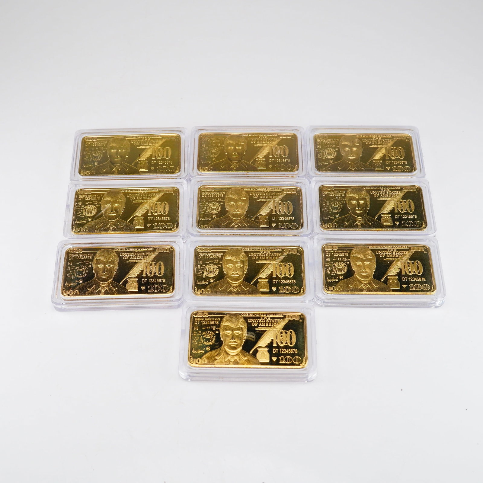 Ten Berkley Jensen 100 Unit Commemorative Donald Trump 24K Gold-Plated Bars: A set of ten contemporary commemorative bars from the Berkley Jensen 100 unit series, designed with motifs inspired by United States currency. Each bar is constructed from gold-plated metal and is ind