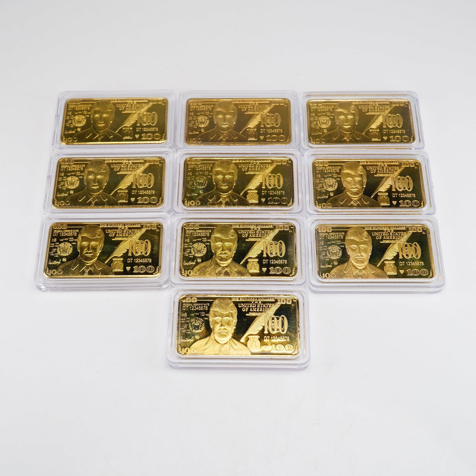 10pc Berkley Jensen Donald Trump Commemorative 24 Karat Gold Plated 100 Unit Bars: This lot consists of 10 commemorative novelty bars produced by Berkley Jensen, featuring the likeness of Donald Trump. Each bar is designed to replicate the aesthetic of a modern United States 100 dol
