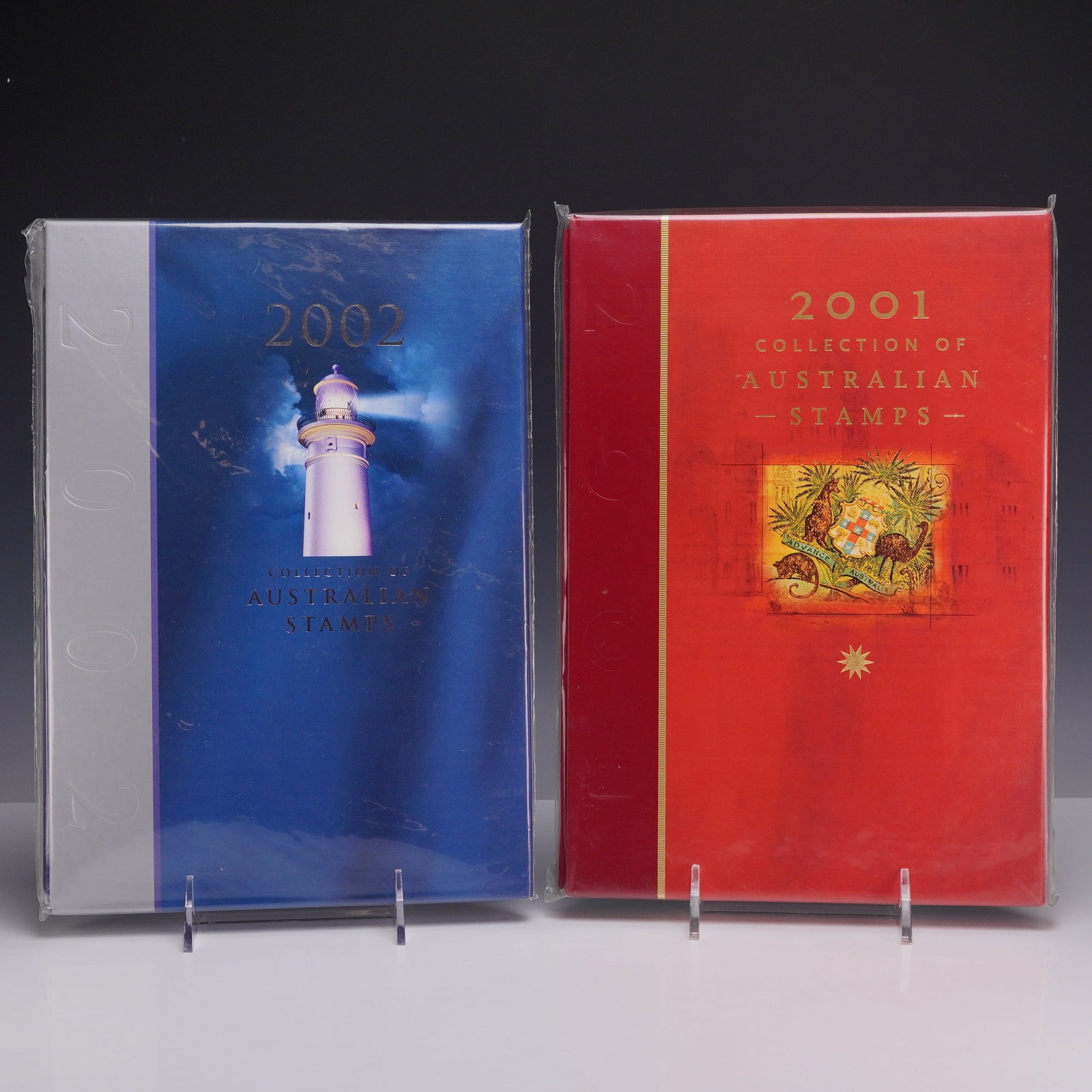 Two Collection of Australian Stamps Deluxe Edition Yearbooks 2001 and 2002, MNH: Two Australia Post Deluxe Edition yearbooks comprising the 2001 and 2002 Collections of Australian Stamps. The 2001 volume is bound in red with gold-tone lettering and features the Australian Coat of 