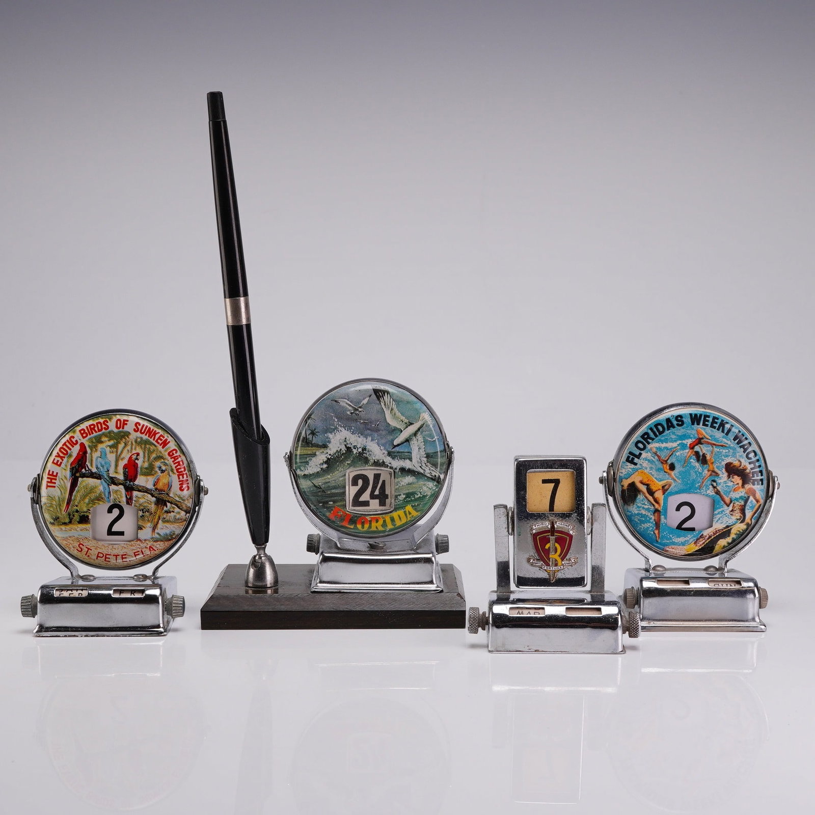 Collection of 4 Vintage Chrome Perpetual Roll Top Desk Calendars: This collection features 4 roll top calendar units manufactured in Japan during the mid-20th century. The group includes three Florida tourism souvenirs and one United States military commemorative it