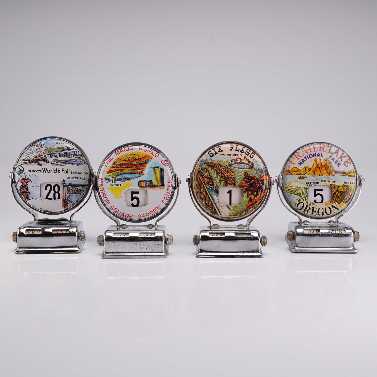 Collection of 4 Vintage Chrome Perpetual Roll Top Flip Desk Calendars: This collection includes 4 roll top calendar units featuring vintage perpetual flip desk mechanisms dating to approximately 1970-1974. Each item is constructed of chrome-plated metal with a rotating c