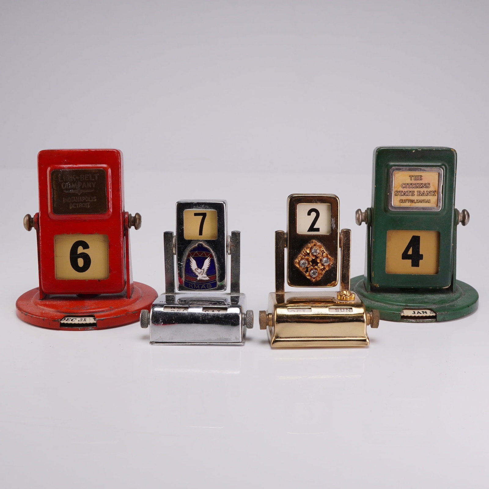 Collection of Four Vintage Metal Perpetual Roll Top Desk Calendars: This collection consists of four mid-century perpetual desk calendars of various designs and promotional origins, including 4 roll top calendar units. The group includes two painted metal flip-style c