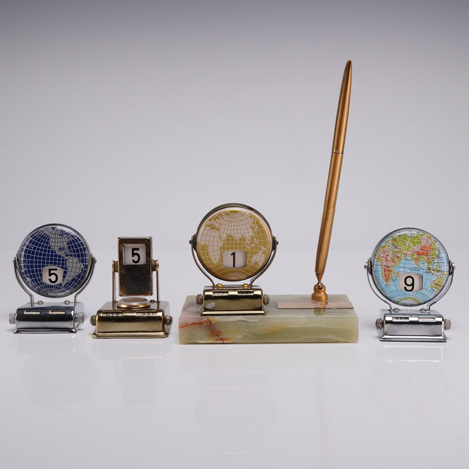 Group of Four MCM Roll Top Perpetual Desk Calendars and Onyx Desk Set: This collection features four mid-century modern perpetual desk calendars, including one integrated desk set. The group contains two chrome-plated 4 roll top calendar units with rotating globes. One g