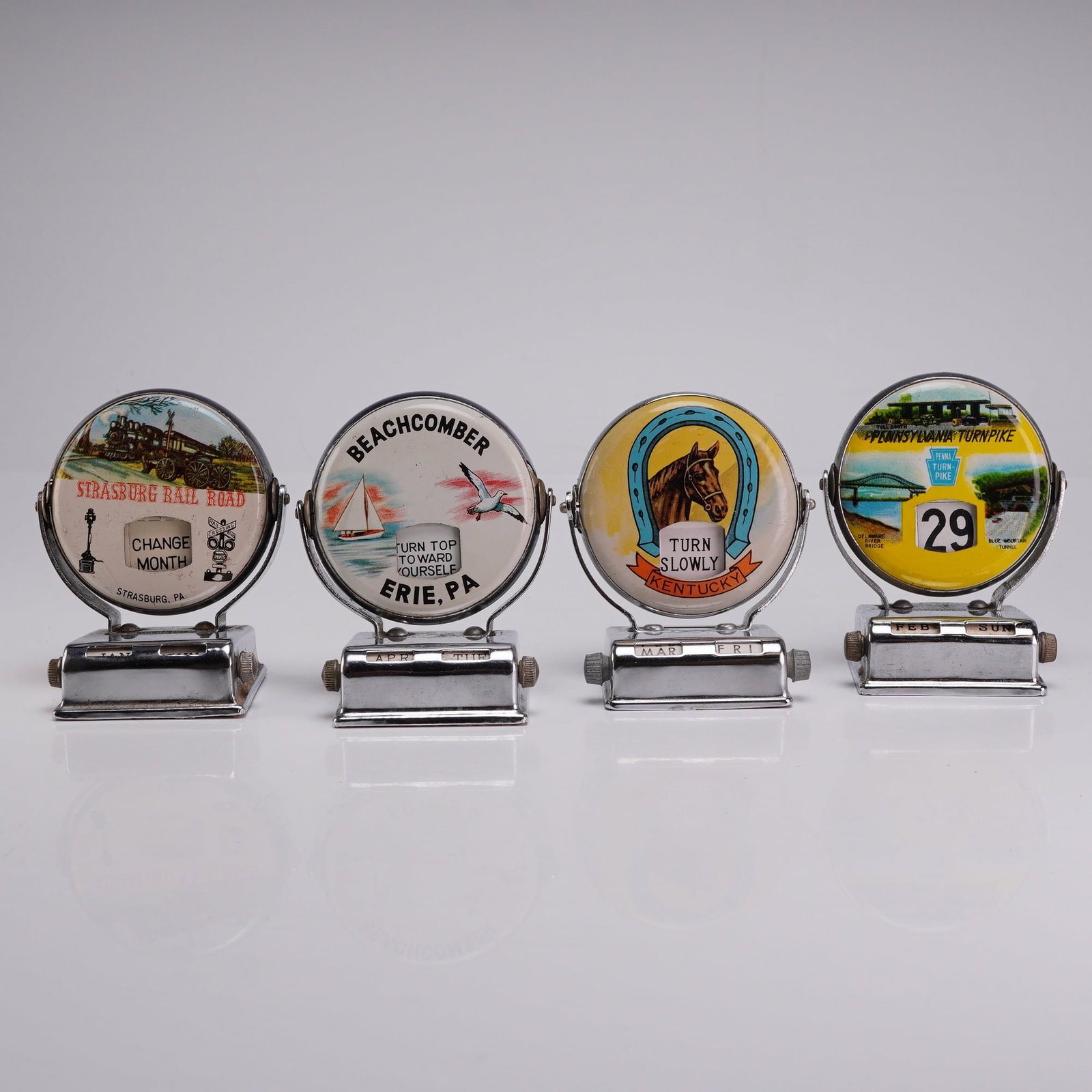 4pc Vintage Chrome Mechanical Roll Top Perpetual Desk Calendars: This collection consists of four mid-20th century mechanical perpetual desk calendars. Each unit is manufactured from chrome-plated metal and features a rotating circular top disc that displays the nu