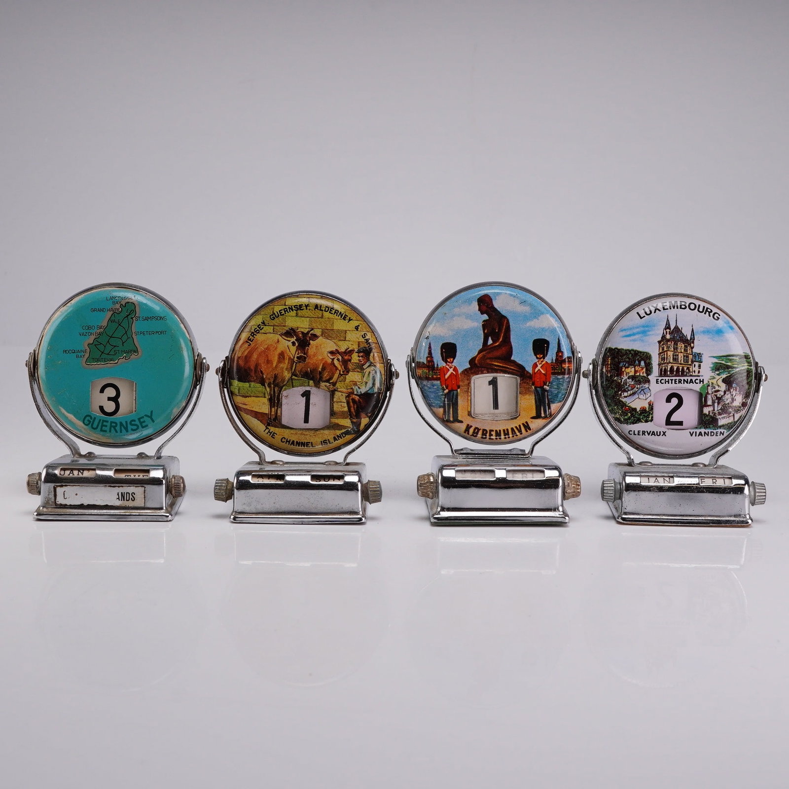 4pc Vintage Chrome Perpetual Flip-Style Roll Top Desk Calendars: This collection consists of 4 roll top calendar units designed as travel souvenirs from the mid-20th century. Each perpetual desk calendar features a manual flip-style mechanism where rotating the cir