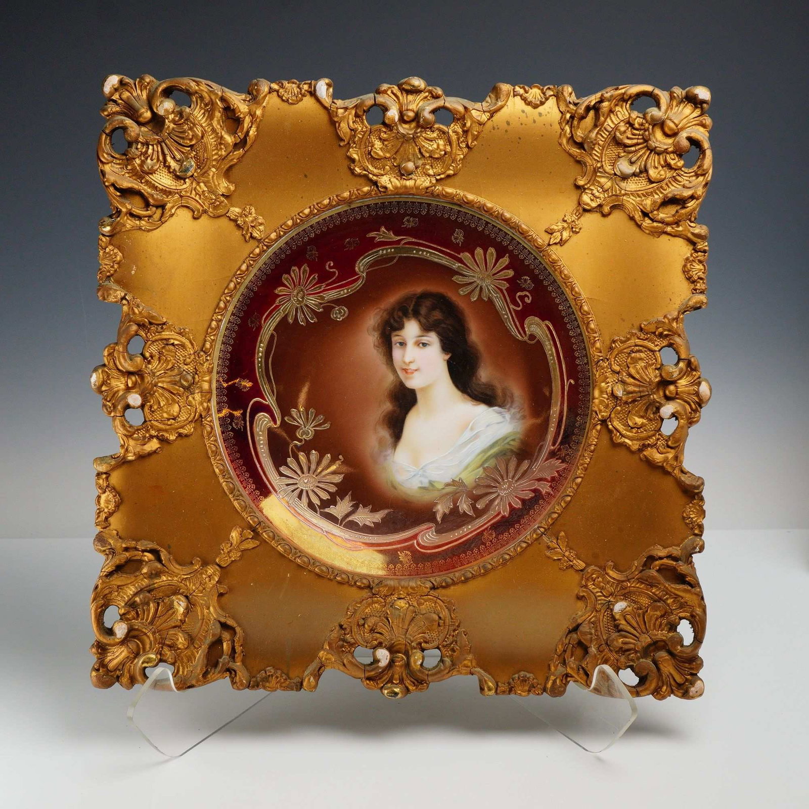 Royal Vienna Porcelain Portrait Plate in Ornate Gilt Frame: A Royal Vienna porcelain portrait plate mounted in an ornate square gilt frame with pierced and raised foliate decoration. The circular plate features a painted female portrait at the center, surround