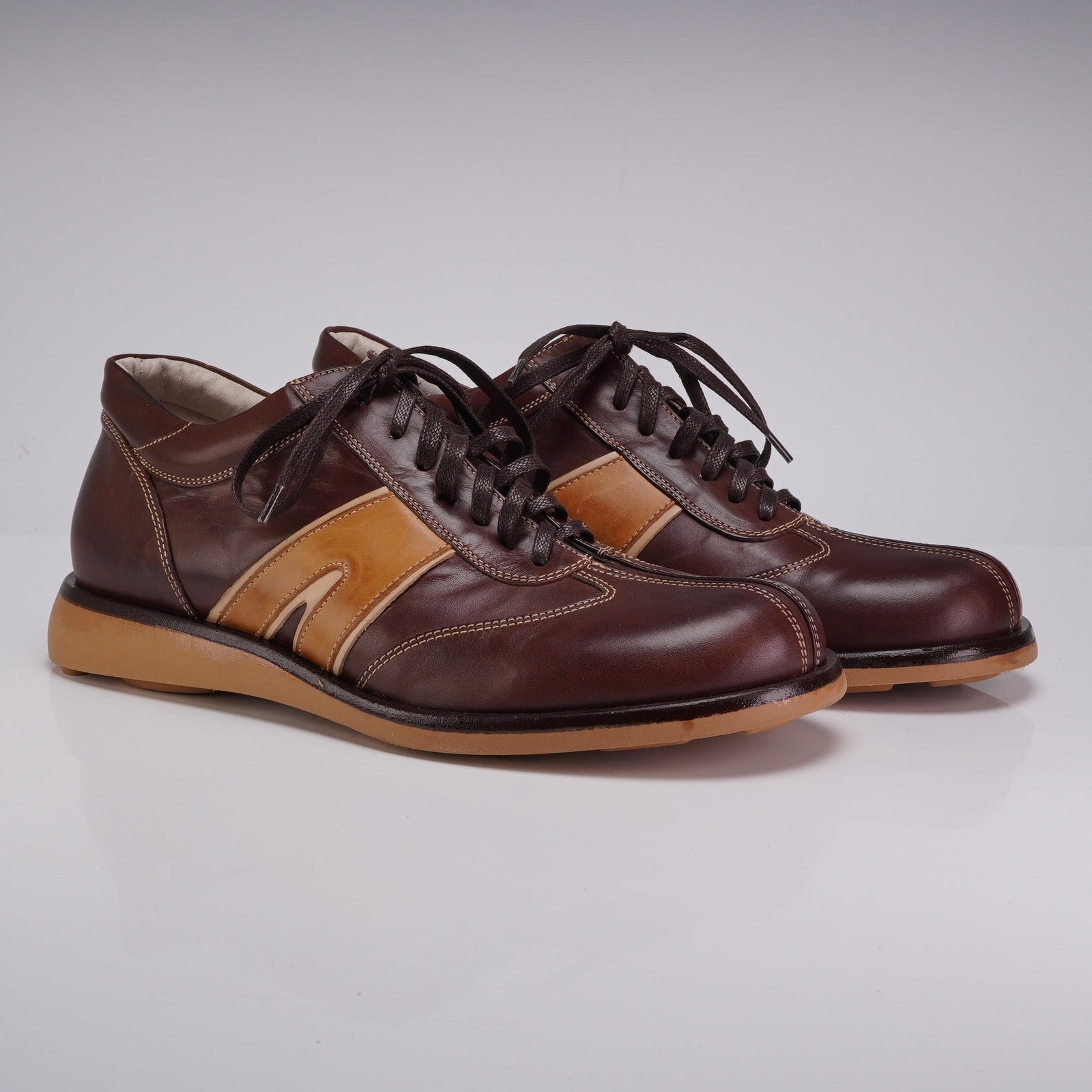 Pair of DICO by Corvari Men's Two-Tone Leather Casual Shoes: This pair of DICO brand men's casual lace-up shoes features a retro-athletic design. The uppers are constructed from dark brown leather with light tan leather side inlays and contrasting cream-colored