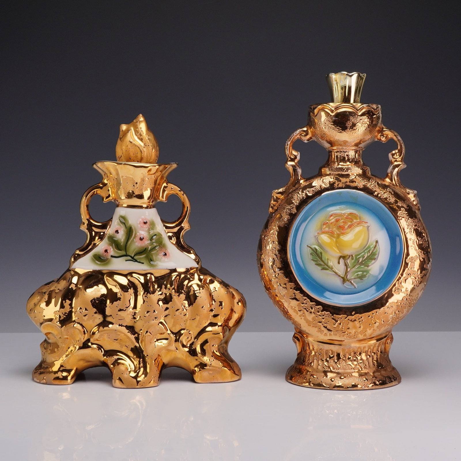 Two Regal China Gold Decorated Porcelain Liquor Bottles for James B. Beam Distilling Co.: This lot consists of two vintage ceramic liquor decanters produced in 1970 by the Regal China Corporation for the James B. Beam Distilling Co. Both vessels are finished in a heavily textured gold lust