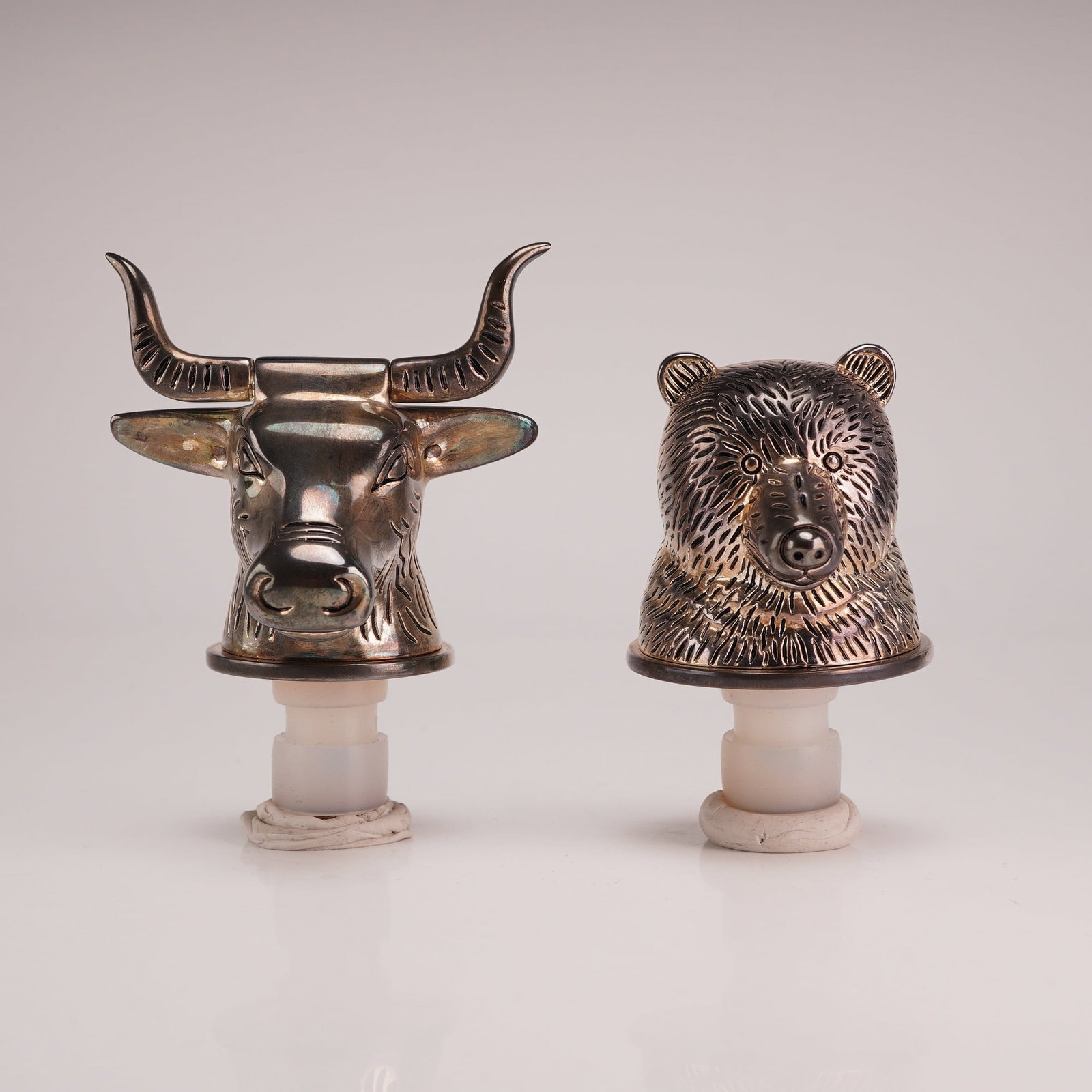 A Pair of Neiman Marcus Silver Plated Bull and Bear Wine Bottle Stoppers: This set of two wine bottle stoppers was retailed by Neiman Marcus and features the financial market motifs of a bull and a bear. The stoppers are constructed from cast metal with a silver-plated fini