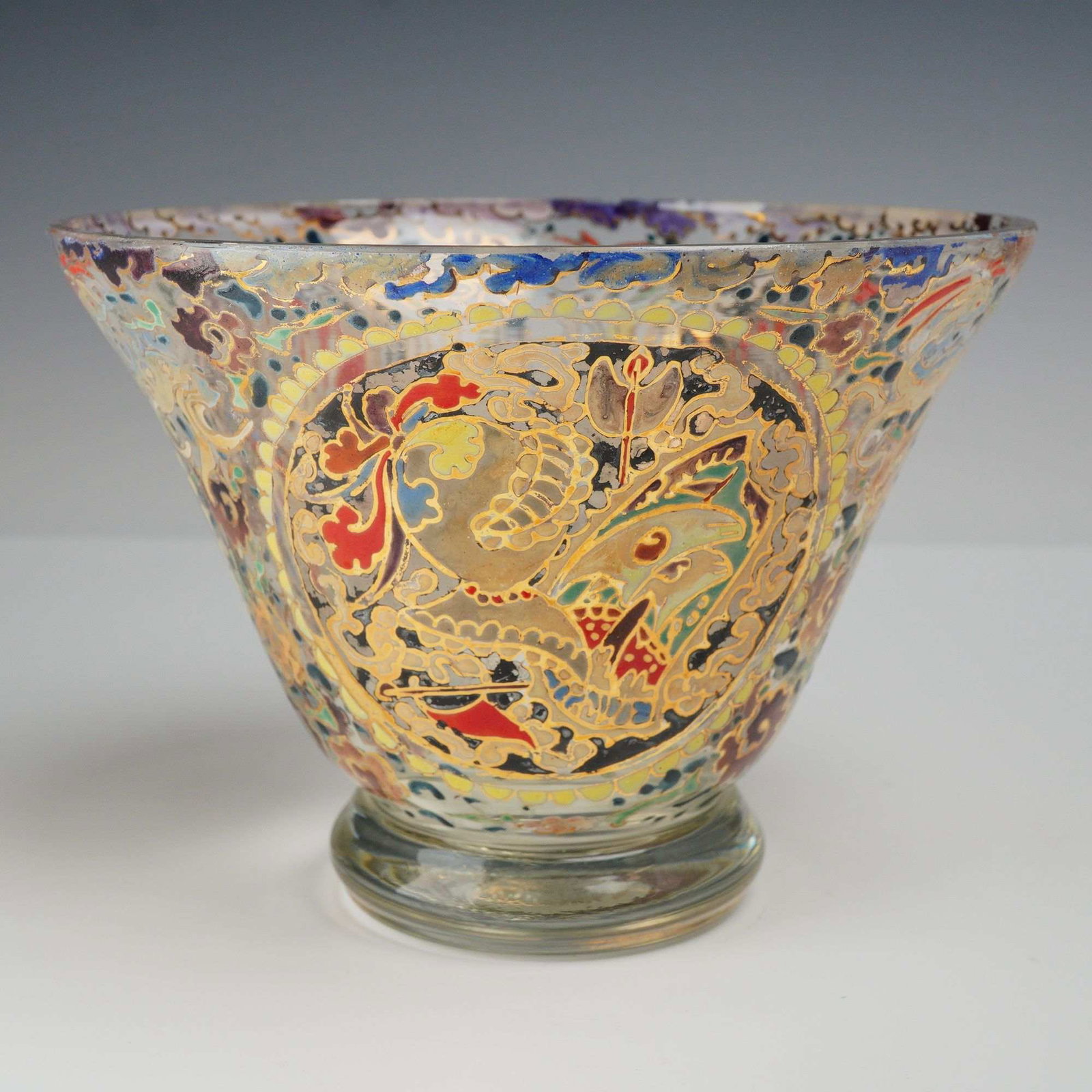 Bohemian Style Hand Enameled and Gilt Glass Bowl: A decorative clear glass bowl with flared sides and a circular foot, richly decorated with multicolor enamel and gilt designs. The exterior features repeating paisley-style reserves, floral scrollwork
