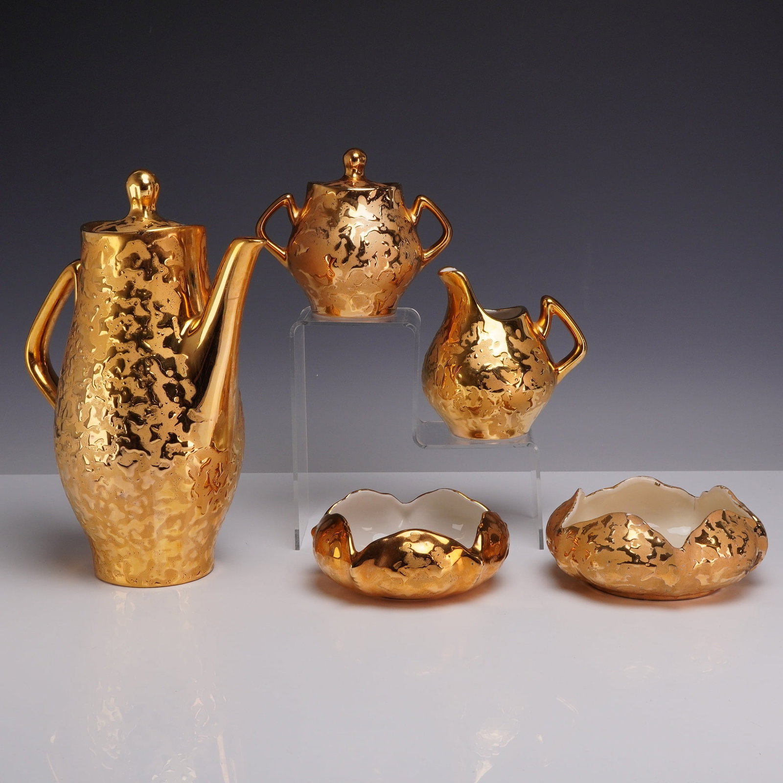 5pc 22 Karat Gold Hand Decorated Porcelain Coffee Pot, Creamer, Lidded Sugar, and Bowls: This five-piece mid-century American ceramic coffee service is finished in a heavy, textured gold glaze often referred to as weeping gold. The set includes a tall, tapered Coffee Pot with a matching l