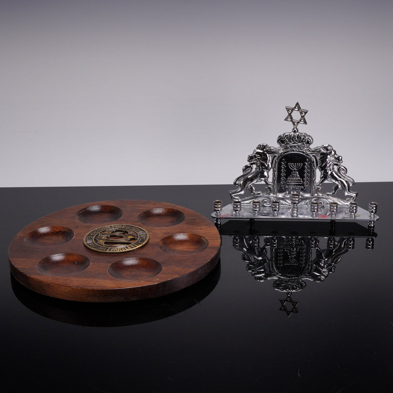 Two-Piece Judaica Set Including Chrome-Plated Menorah and Carved Wood Seder Plate: This lot consists of two pieces of contemporary Judaica including a Hanukkah menorah and a Passover Seder plate. The Hanukkah menorah is constructed of cast metal with a polished chrome-plated finish.