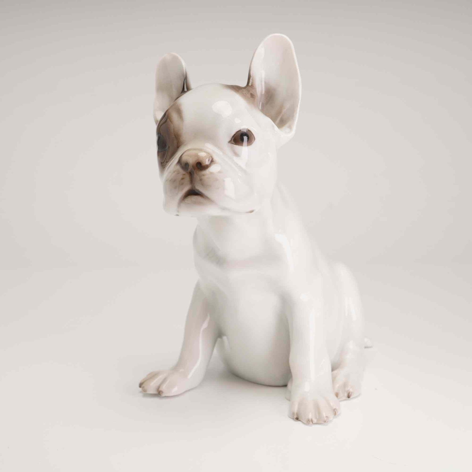 Rosenthal Selb-Bavaria Porcelain French Bulldog Figurine: This polychrome glazed porcelain figurine depicts a seated French Bulldog, modeled in a naturalistic pose. The dog is rendered with a white ground and features soft grey-brown markings around the left