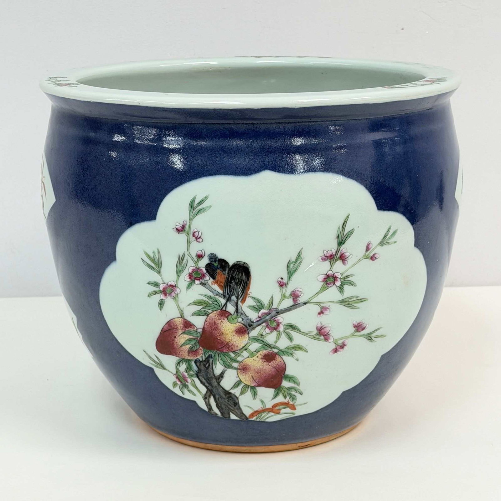 Chinese Porcelain Jardiniere with Powder Blue Glaze and Famille Rose Reserves: This Chinese porcelain jardiniere features a powder blue glaze on the exterior body. The vessel is decorated with various white-ground reserves rendered in famille rose polychrome enamels. The primary
