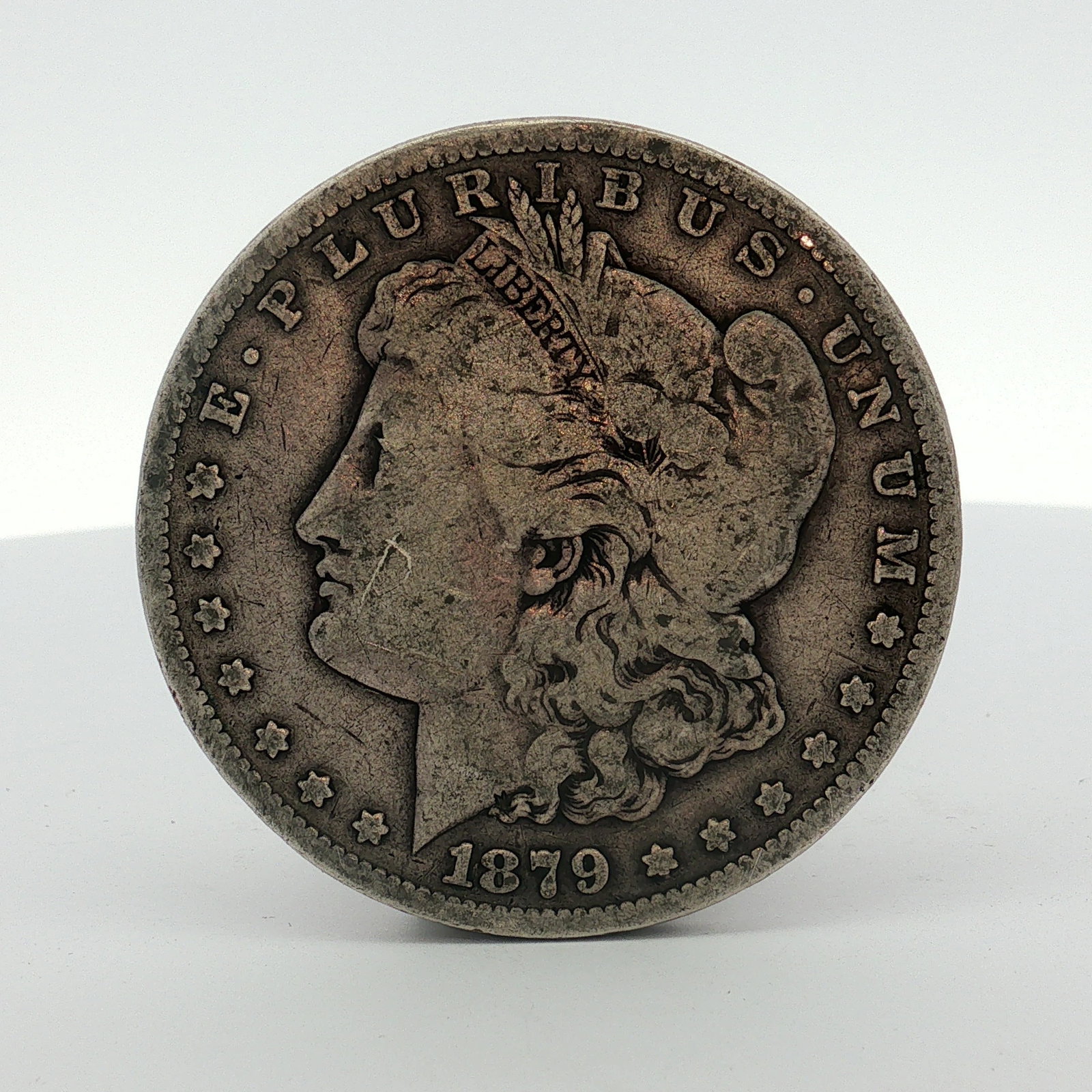 1879-S US One Dollar Morgan Silver Dollar, Circulated: This 1879 US Morgan silver dollar was struck at the San Francisco mint. The coin is composed of 90% silver. It features the standard Morgan dollar obverse and reverse design types. The edge is reeded.