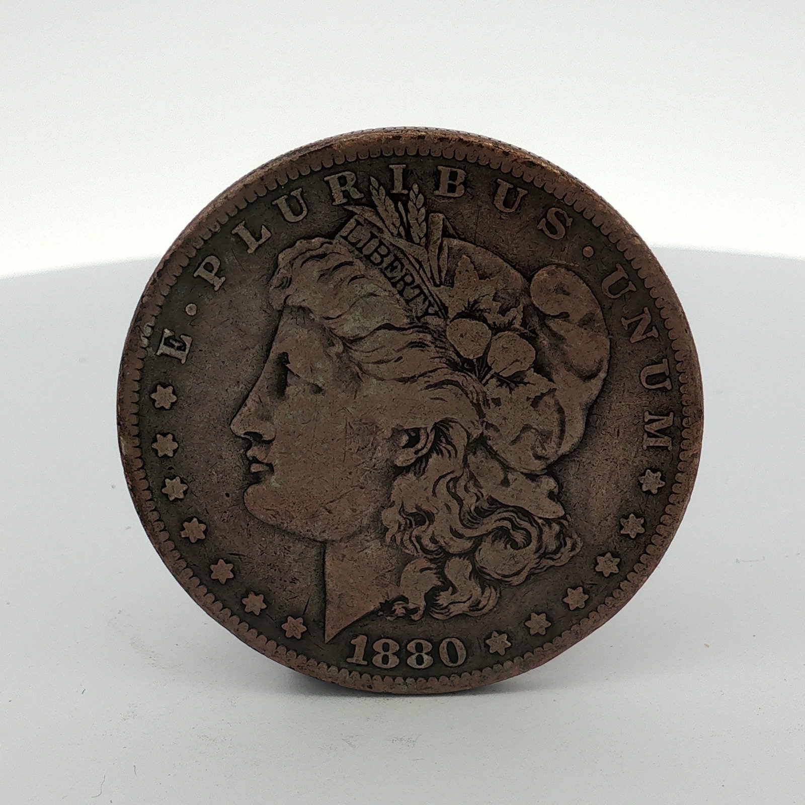 1880 US One Dollar Morgan Silver Dollar, Circulated: 1880 US Morgan Silver Dollar, Philadelphia Mint. This Morgan dollar features the Liberty head obverse and heraldic eagle reverse. The obverse is inscribed E PLURIBUS UNUM and the date 1880. The revers