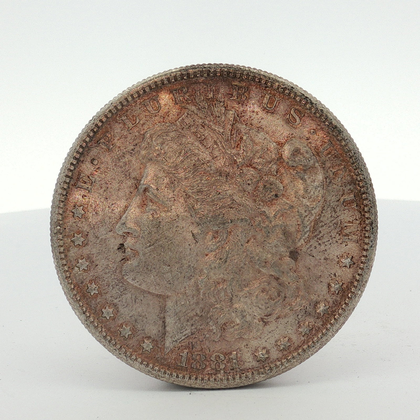 1881-S US One Dollar Morgan Silver Dollar, Circulated: This coin is composed of 90% silver and 10% copper. It features a reeded edge and two distinct C mint marks positioned on the reverse below the wreath, identifying it as a Carson City Mint strike. The