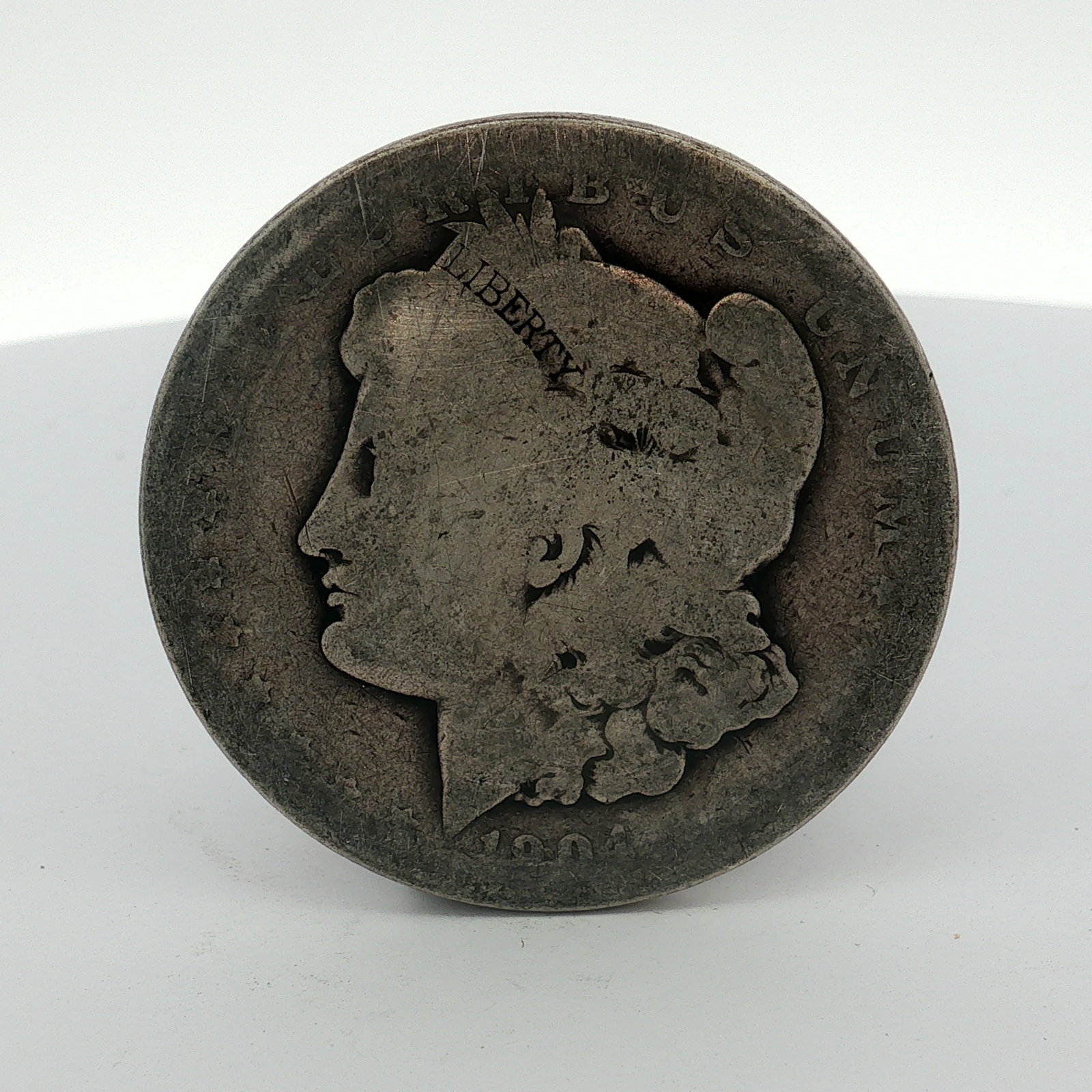 1884 US One Dollar Morgan Silver Dollar, Circulated: This 90% silver coin was produced using a struck construction method and features the Morgan dollar obverse and reverse designs. The obverse is inscribed with the legend E PLURIBUS UNUM and the date 1