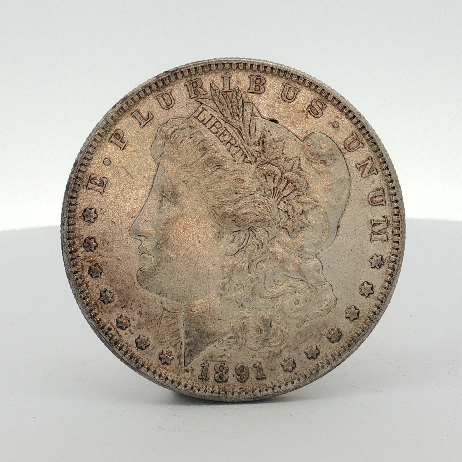 1891-S US One Dollar Morgan Silver Dollar, Circulated: This US 1891-S Morgan silver dollar was struck at the San Francisco Mint. The coin features the Morgan Liberty head obverse and the Morgan eagle reverse. The obverse is inscribed with the motto E PLUR