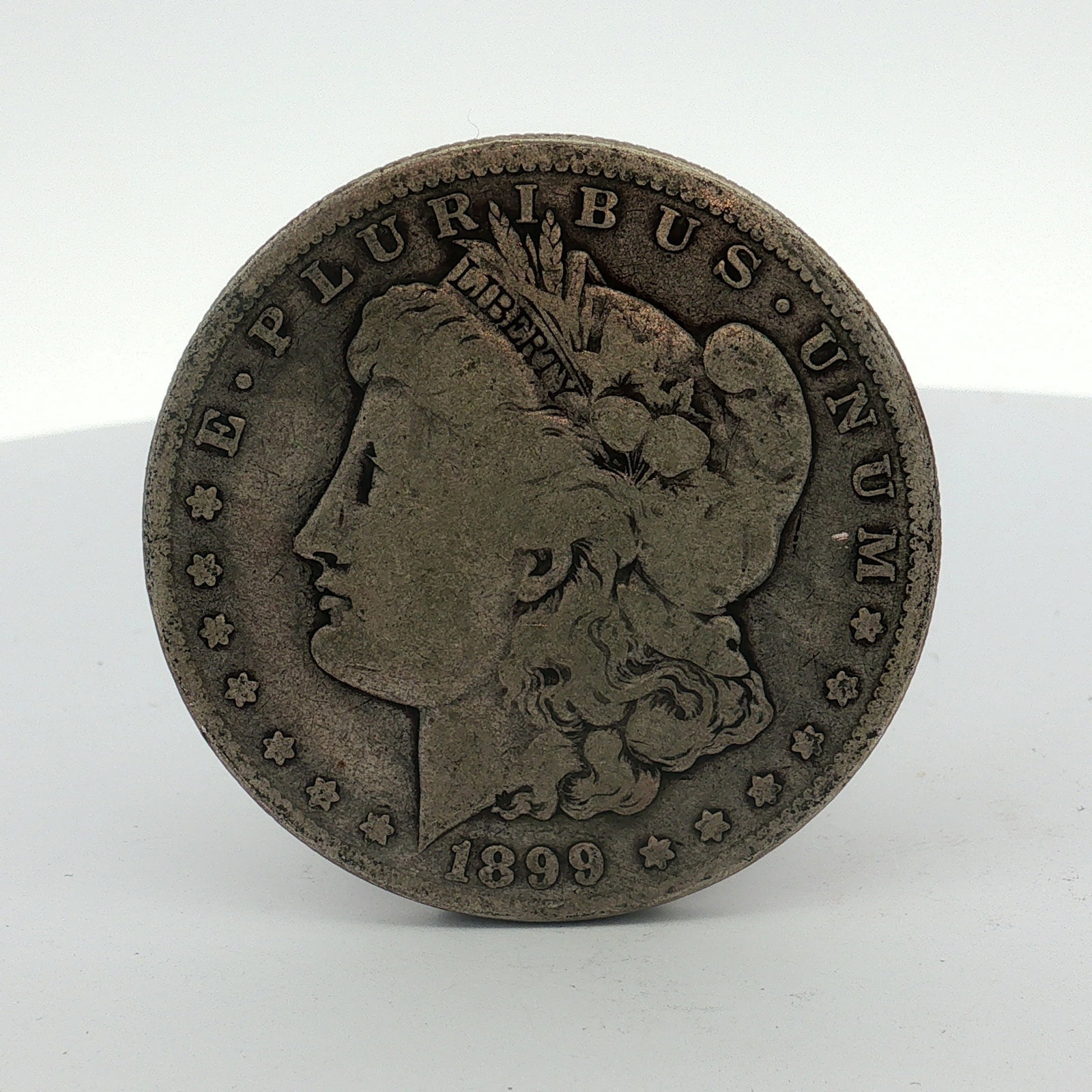 1899-O US Morgan Silver Dollar Coin Circulated: This 1899-O US Morgan silver dollar was struck at the New Orleans Mint. The coin is of silver composition with a reeded edge. It features the Morgan Liberty obverse and the Morgan Eagle reverse. A vis